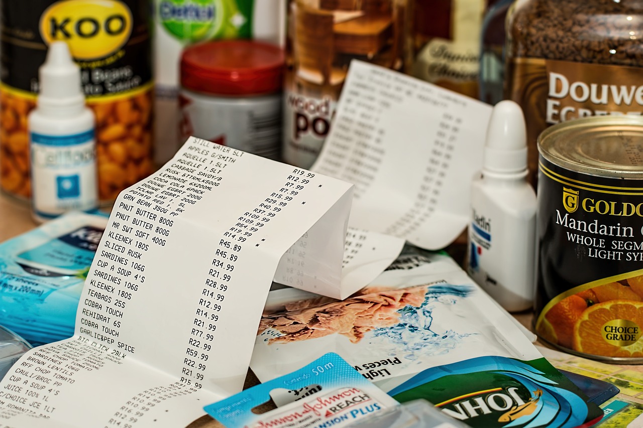 Paragon fiskalny przedstawiający listę produktów spożywczych i ich ceny, symbolizujący ukryte koszty.