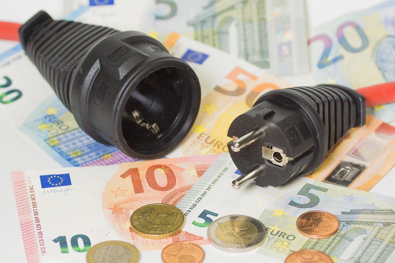 Wtyczka i gniazdko elektryczne na banknotach euro - symbol kosztów budowy elektrowni jądrowej
