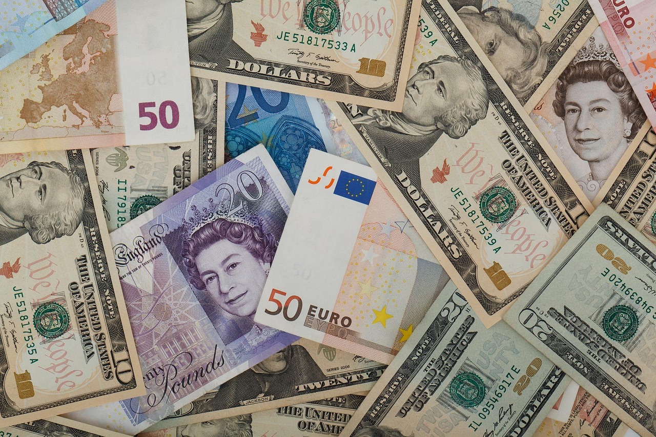Różne waluty, w tym funty brytyjskie, dolary amerykańskie i euro, symbolizujące umowę handlową.