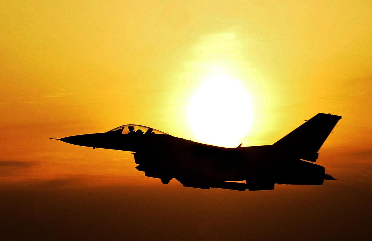 Amerykański myśliwiec F-16 w locie na tle zachodzącego słońca, symbolizujący wzmocnienie obecności wojsk USA w Polsce.