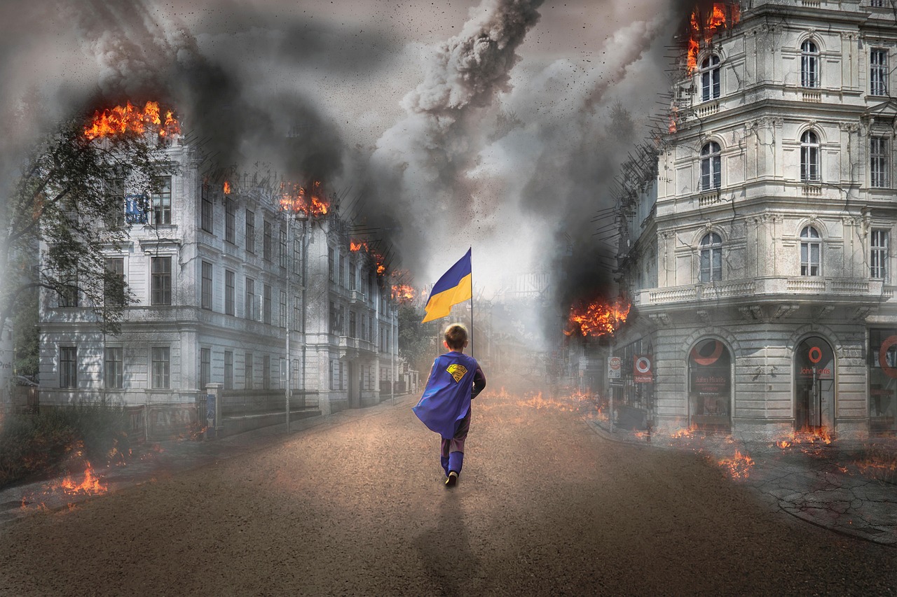 Dziecko w pelerynie Supermana z flagą Ukrainy na tle zniszczonego wojną miasta.