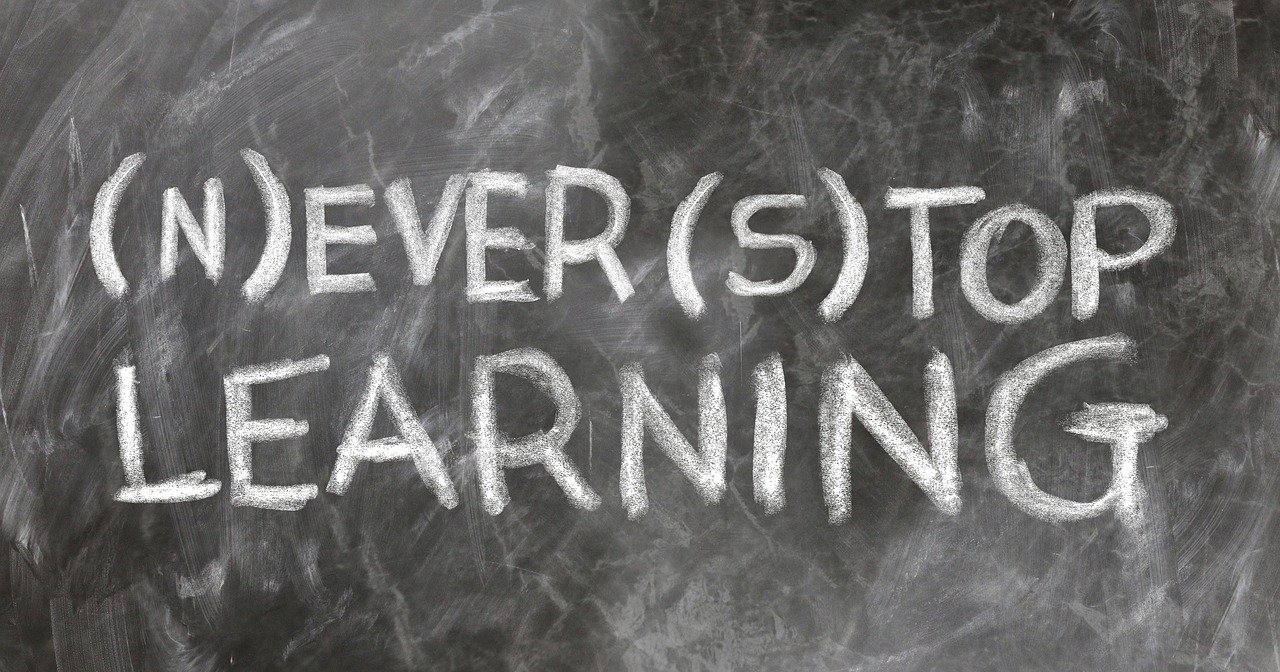 Napis na tablicy kredą: "Never Stop Learning". Informacja o zarobkach nauczycieli w 2025.