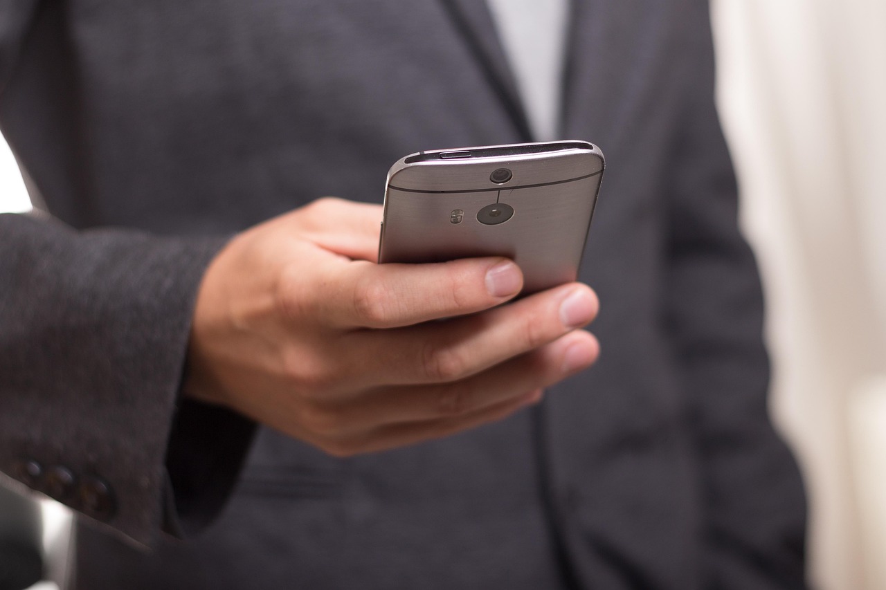 Biznesmen trzyma smartfon, symbolizujący komunikację w banku i potencjalny chaos.