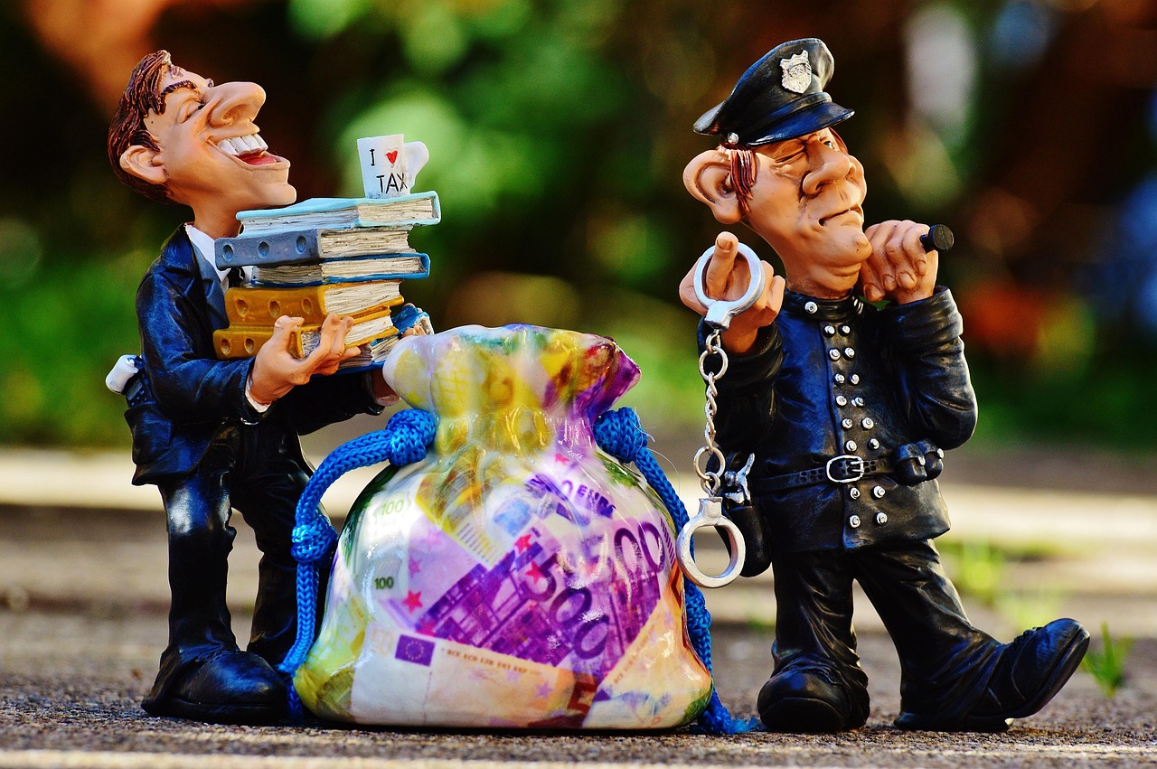 Policjant z kajdankami obok postaci z książkami i torbą pieniędzy, symbolizujący oszustwo na pracownika banku.