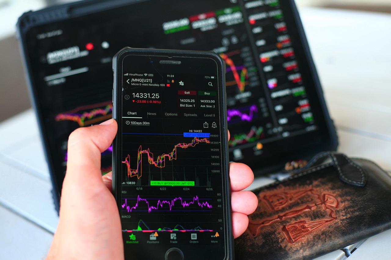 Analiza wykresów giełdowych na smartfonie i tablecie podczas spadku na rynku akcji.