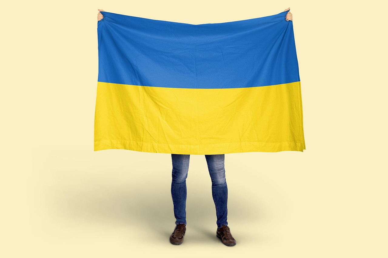 Flaga Ukrainy trzymana przez osobę, symbolizująca wydarzenia we Lwowie.