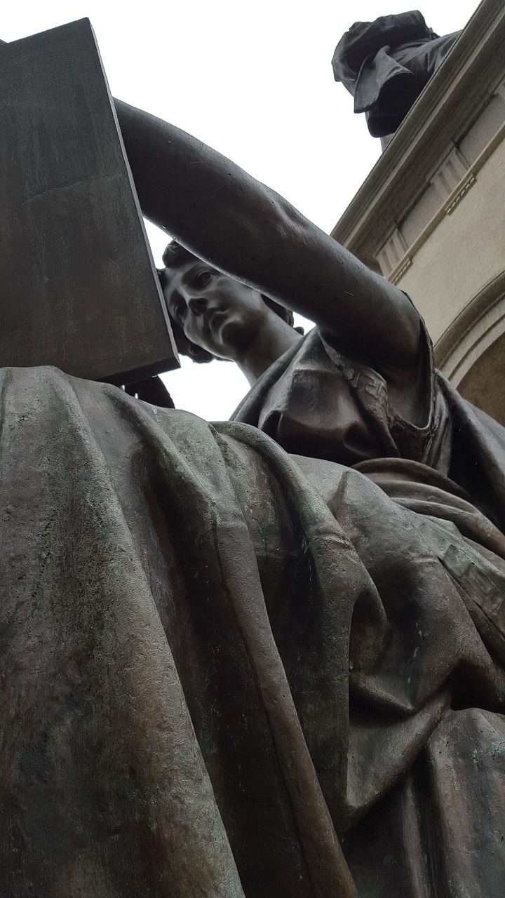 Pomnik przedstawiający postać z księgą, symbolizujący wiedzę i prawo.