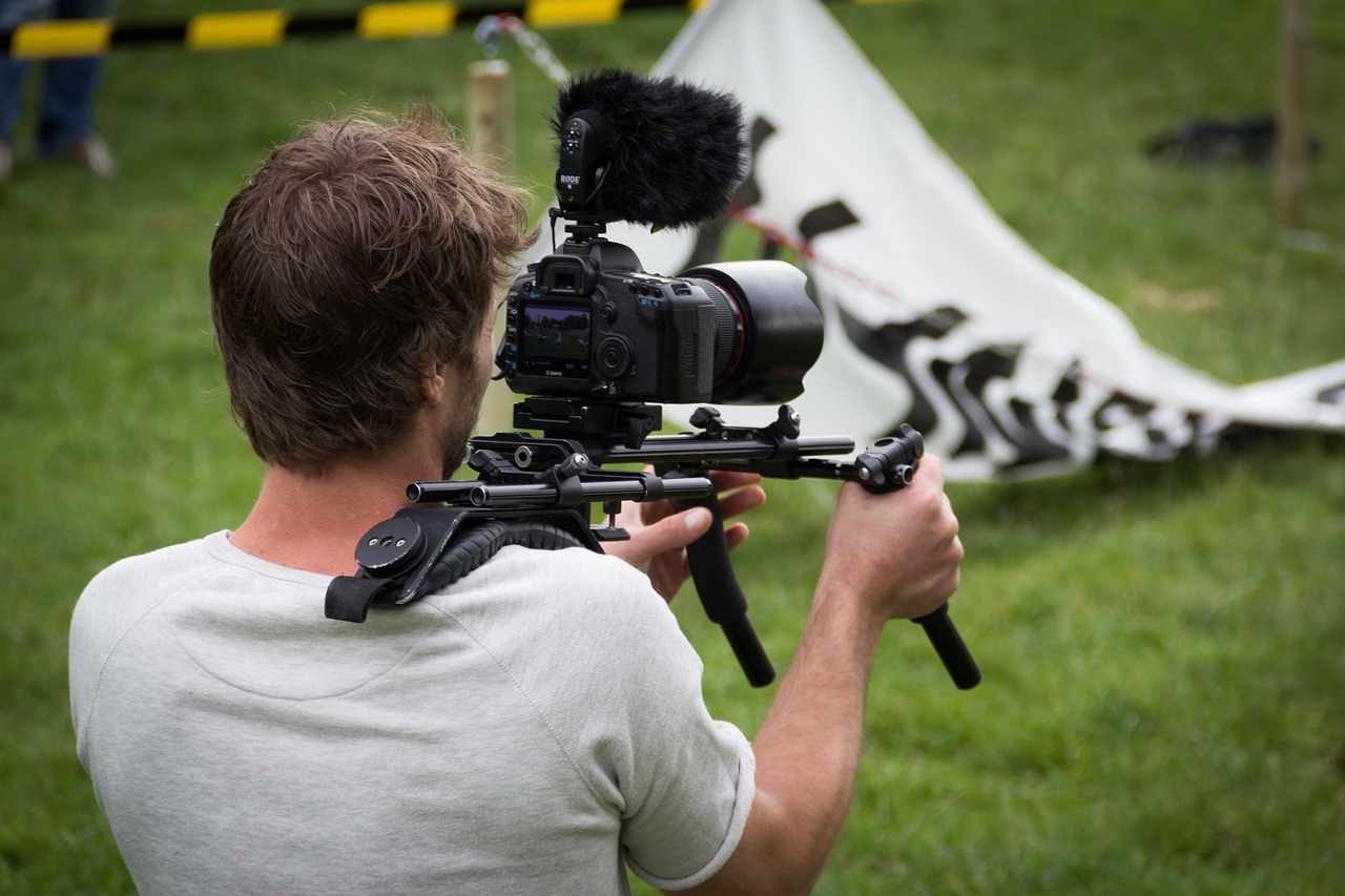 Operator kamery z mikrofonem i stabilizatorem, przygotowujący się do nagrania.