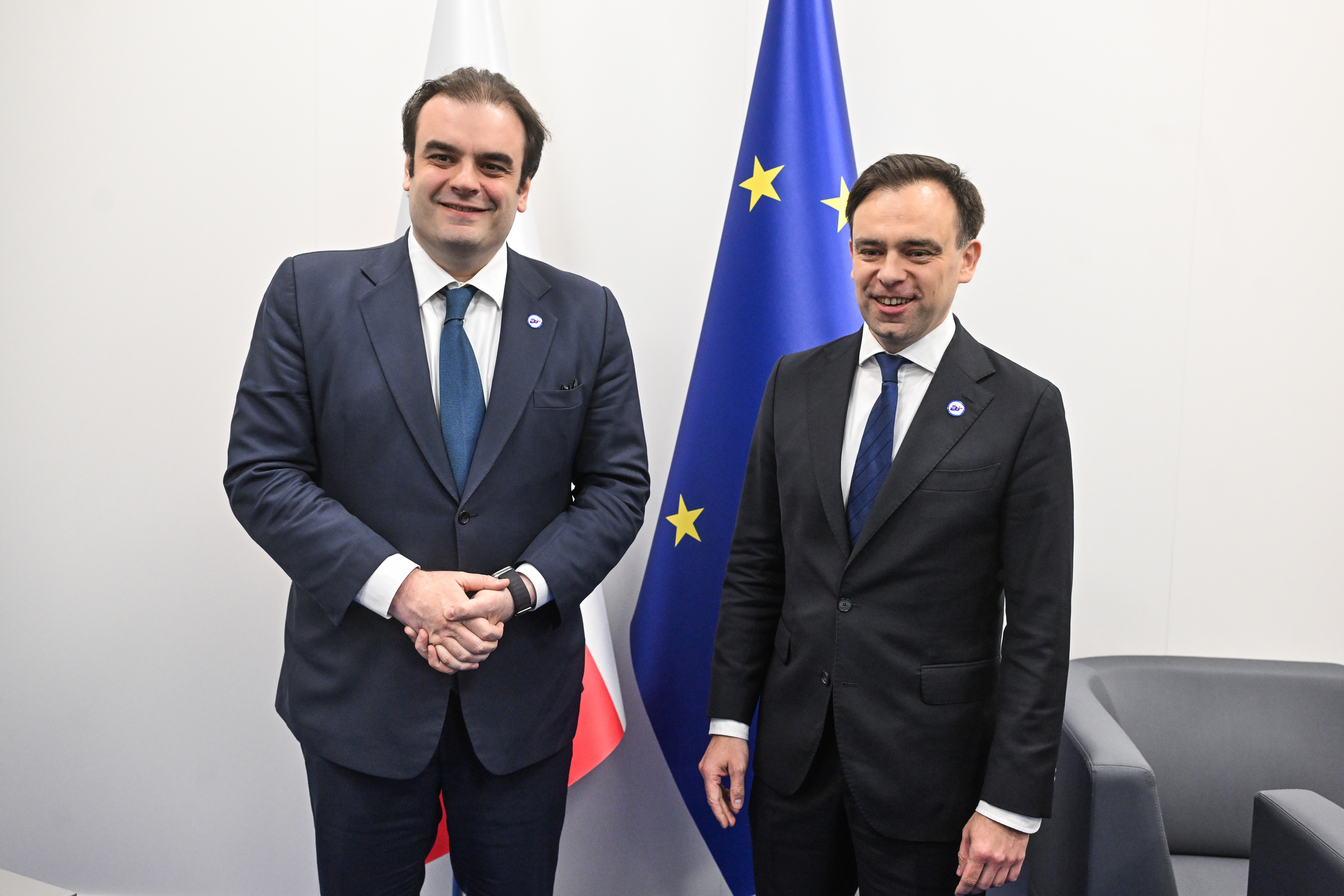 Minister Domański i polityk obok flagi Polski i UE, omawiający rozwiązania dla polskich firm.