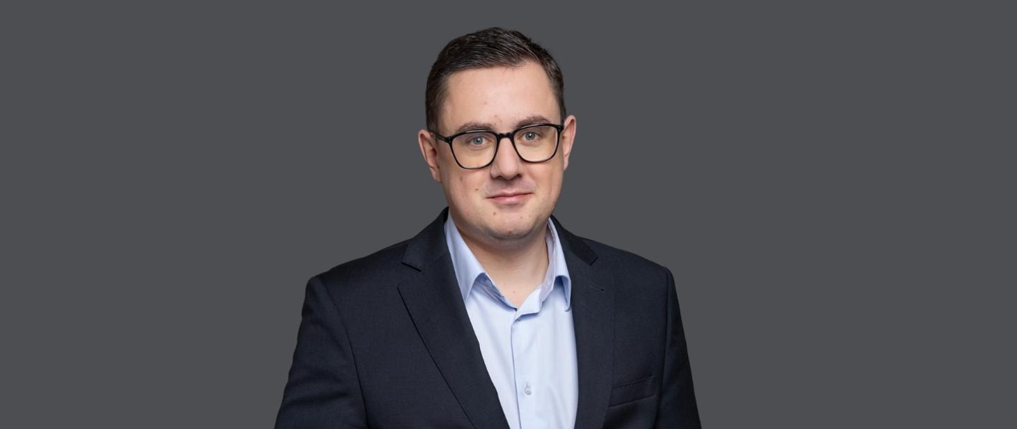 Minister energii Miłosz Motyka w garniturze i okularach, komentuje weto do ustawy o zapasach.