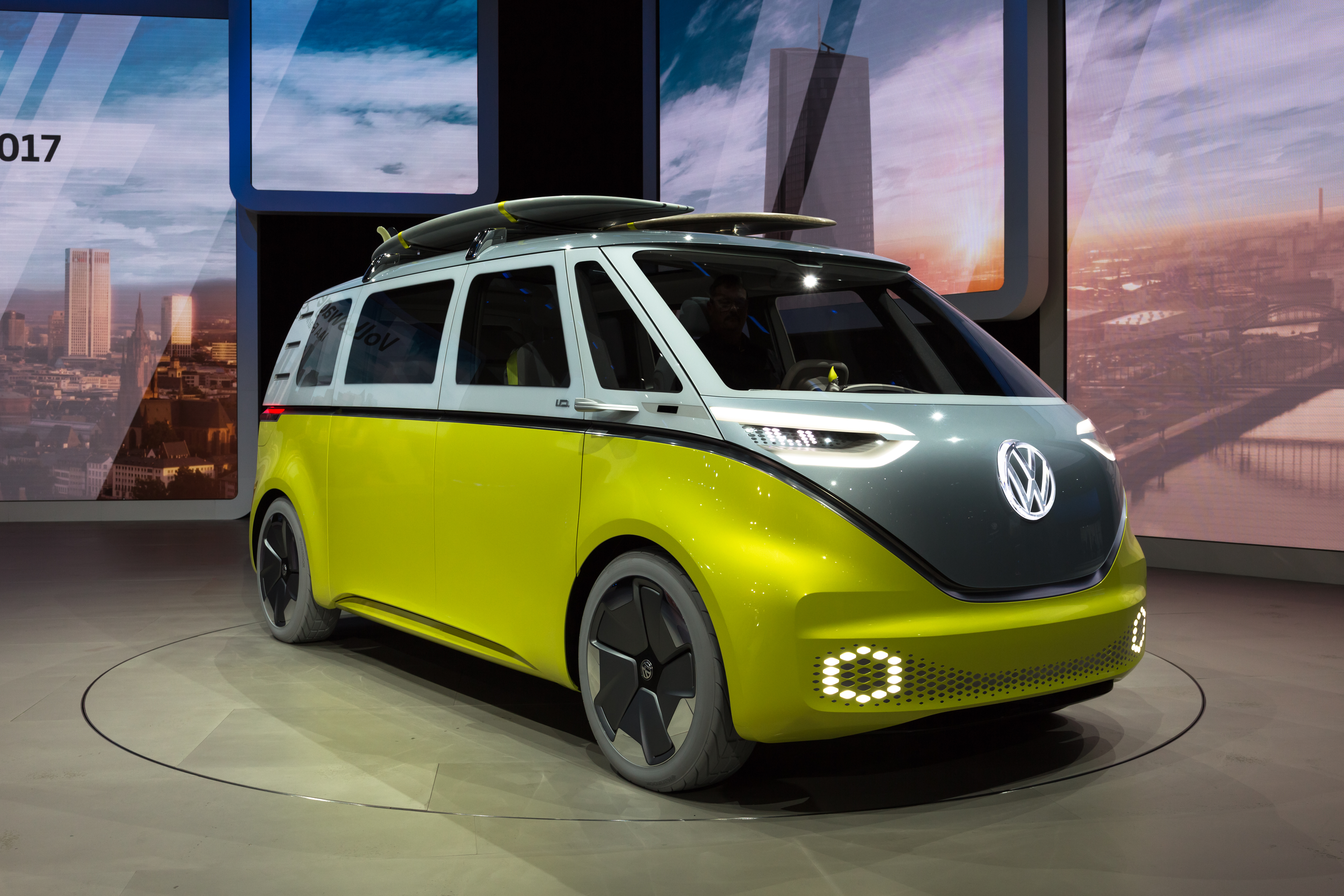 Żółto-szary Volkswagen ID. Buzz na wystawie w 2017 roku, z deskami surfingowymi na dachu.