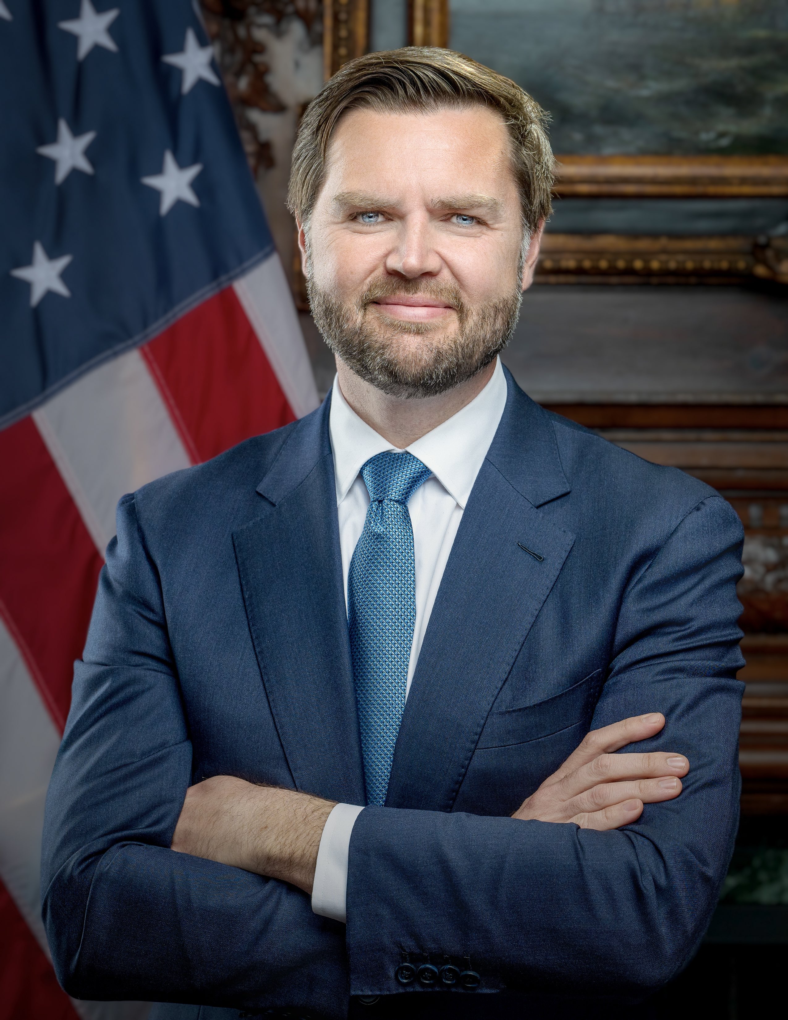 J.D. Vance, amerykański polityk, w garniturze i z flagą USA w tle.