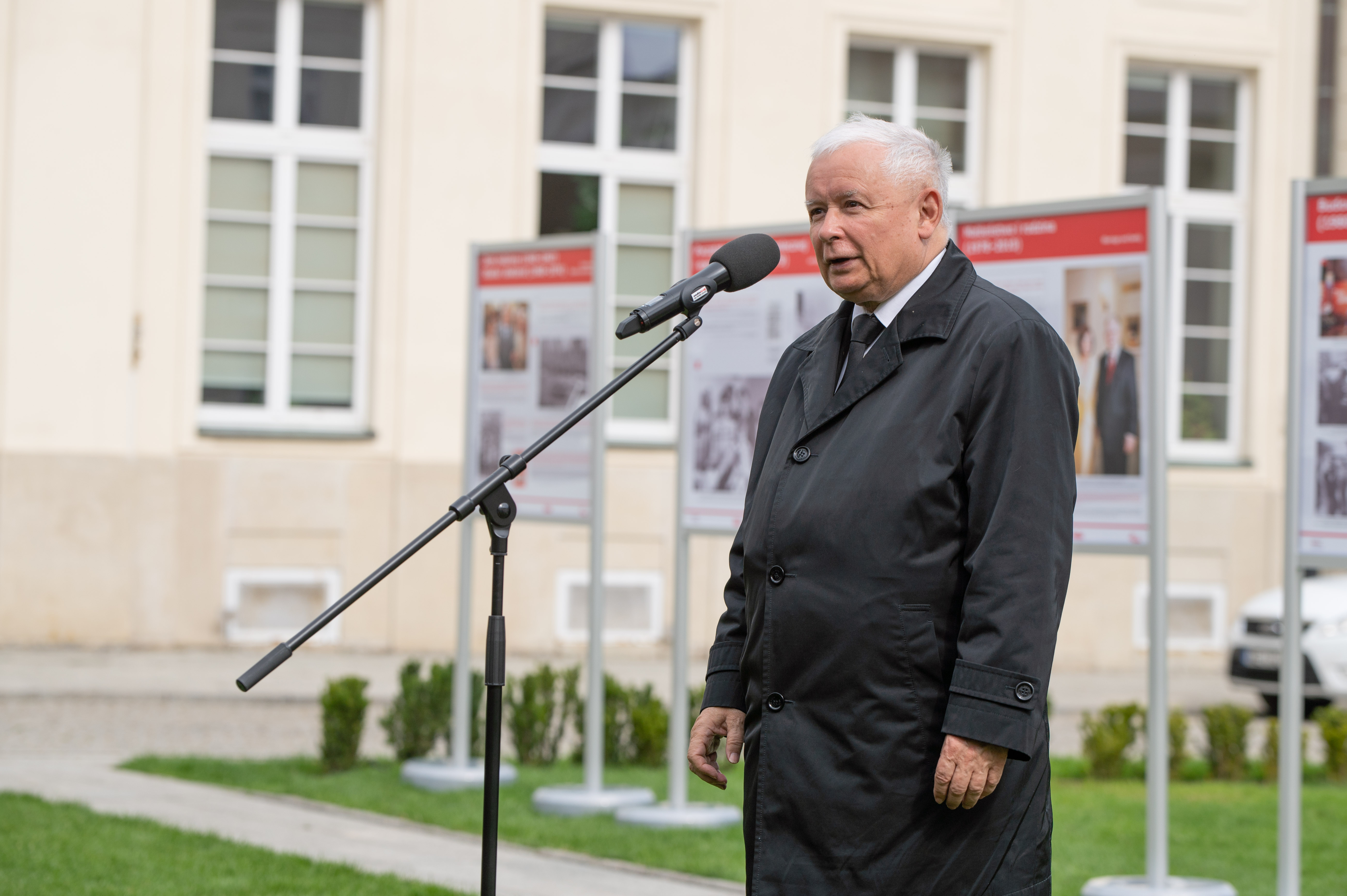 Jarosław Kaczyński przemawia przed mikrofonem, omawiając zagrożenia dla Polski.