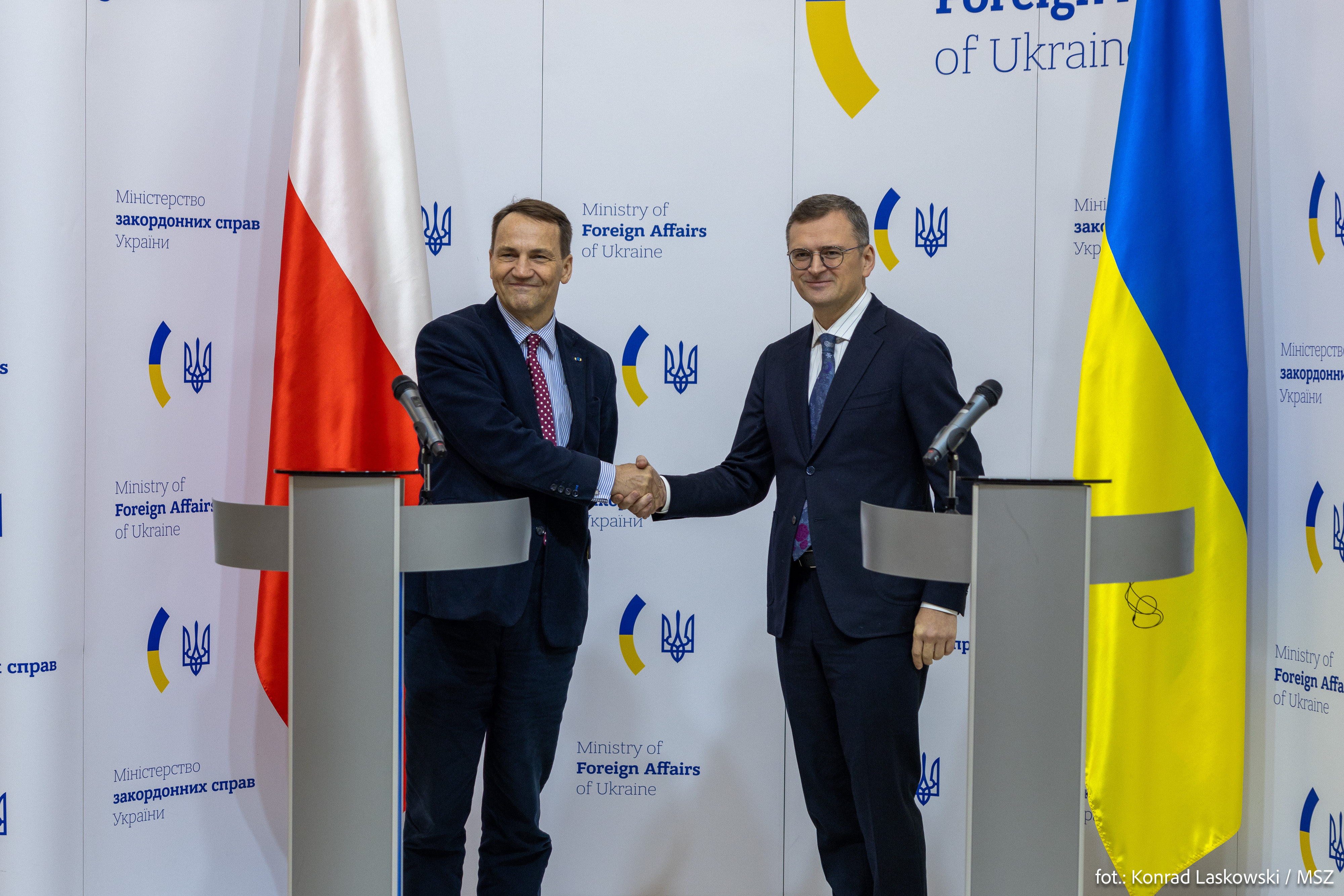 Radosław Sikorski i Dmytro Kuleba uściski dłoni - Polska rusza z pomocą Belgii w obliczu rosyjskich roszczeń.