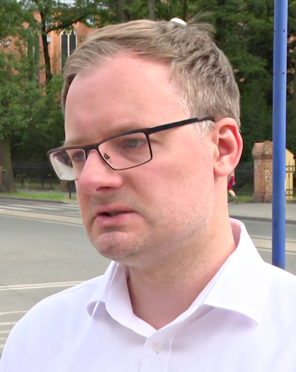Kamil Żbikowski, nowy prezydent Zabrza, w białej koszuli i okularach.