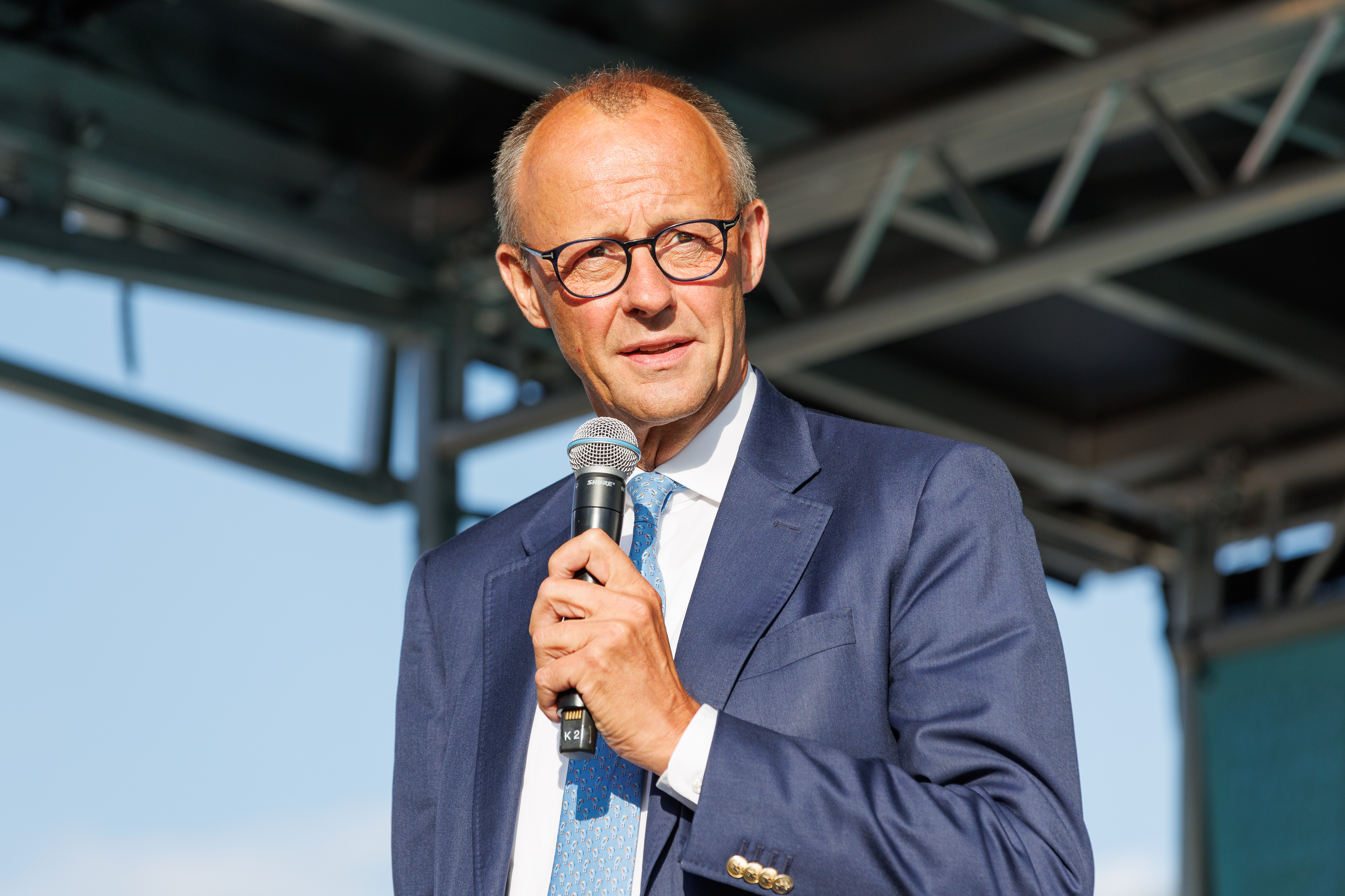 Niemiecki kanclerz Friedrich Merz przemawia do mikrofonu, oceniając rozmowy z Rosją.