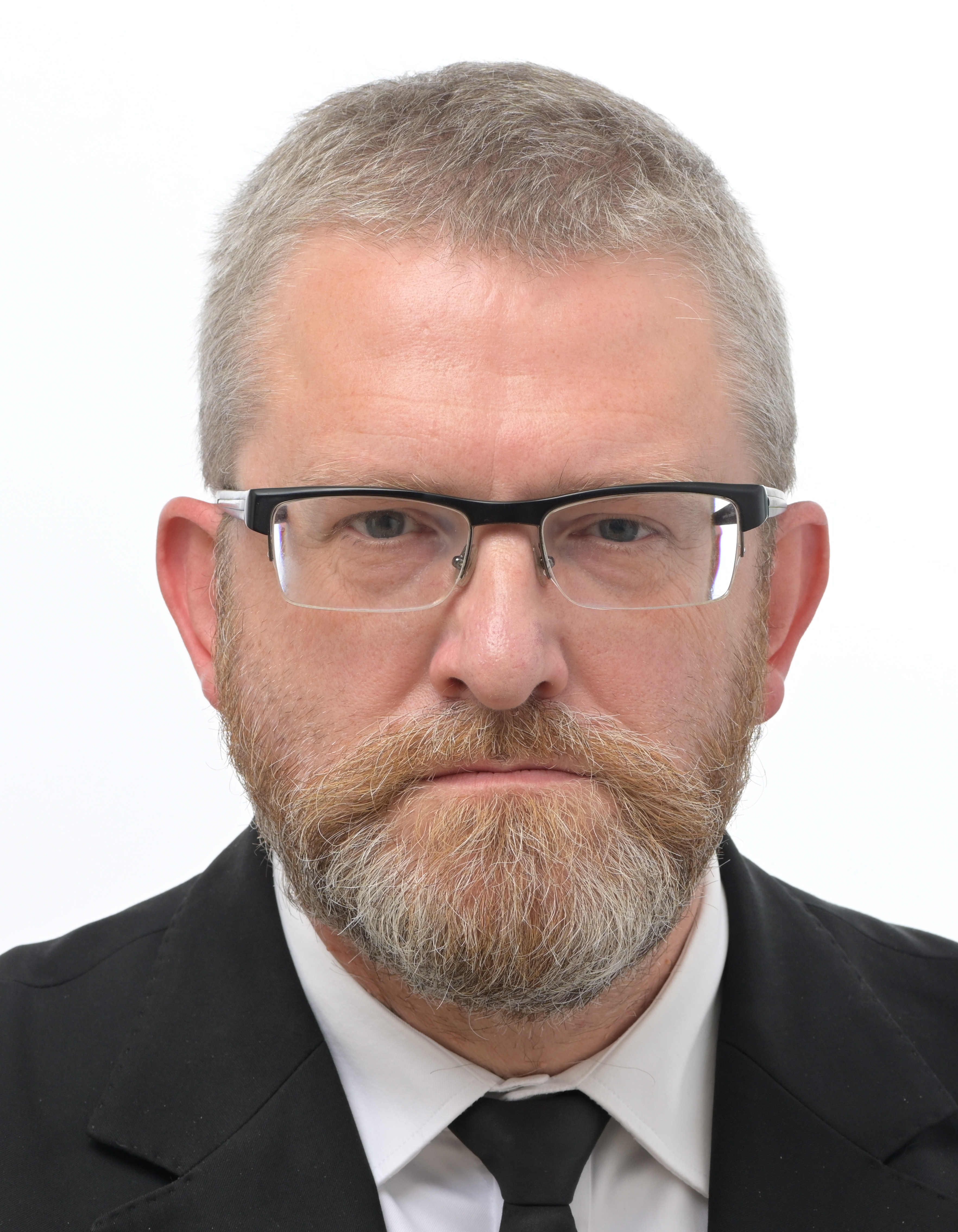 Grzegorz Braun, europoseł, w garniturze i okularach.