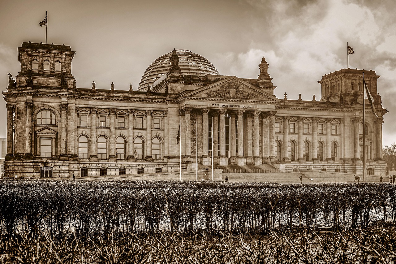 Reichstag w Berlinie, symbol niemieckiej polityki, na tle pochmurnego nieba.