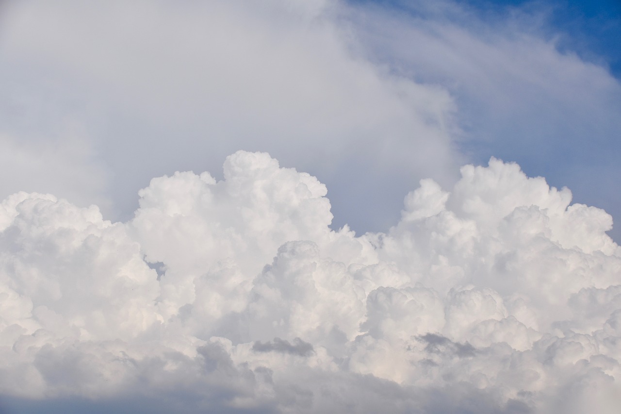 Gęste białe chmury cumulus na tle błękitnego nieba, symbolizujące nadchodzący chłód.