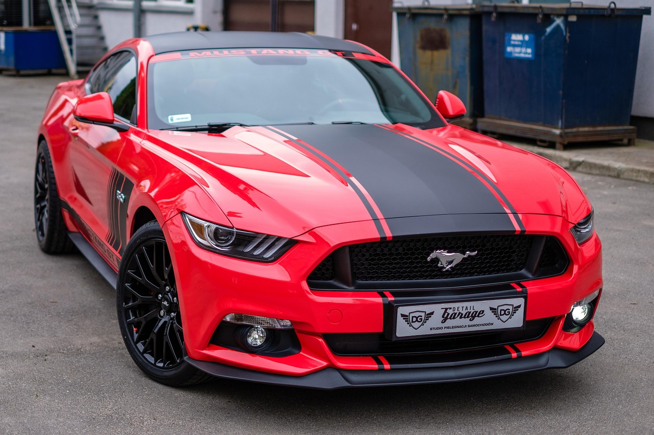 Czerwony Ford Mustang z czarnymi pasami, symbol motoryzacji w debacie o autach spalinowych.