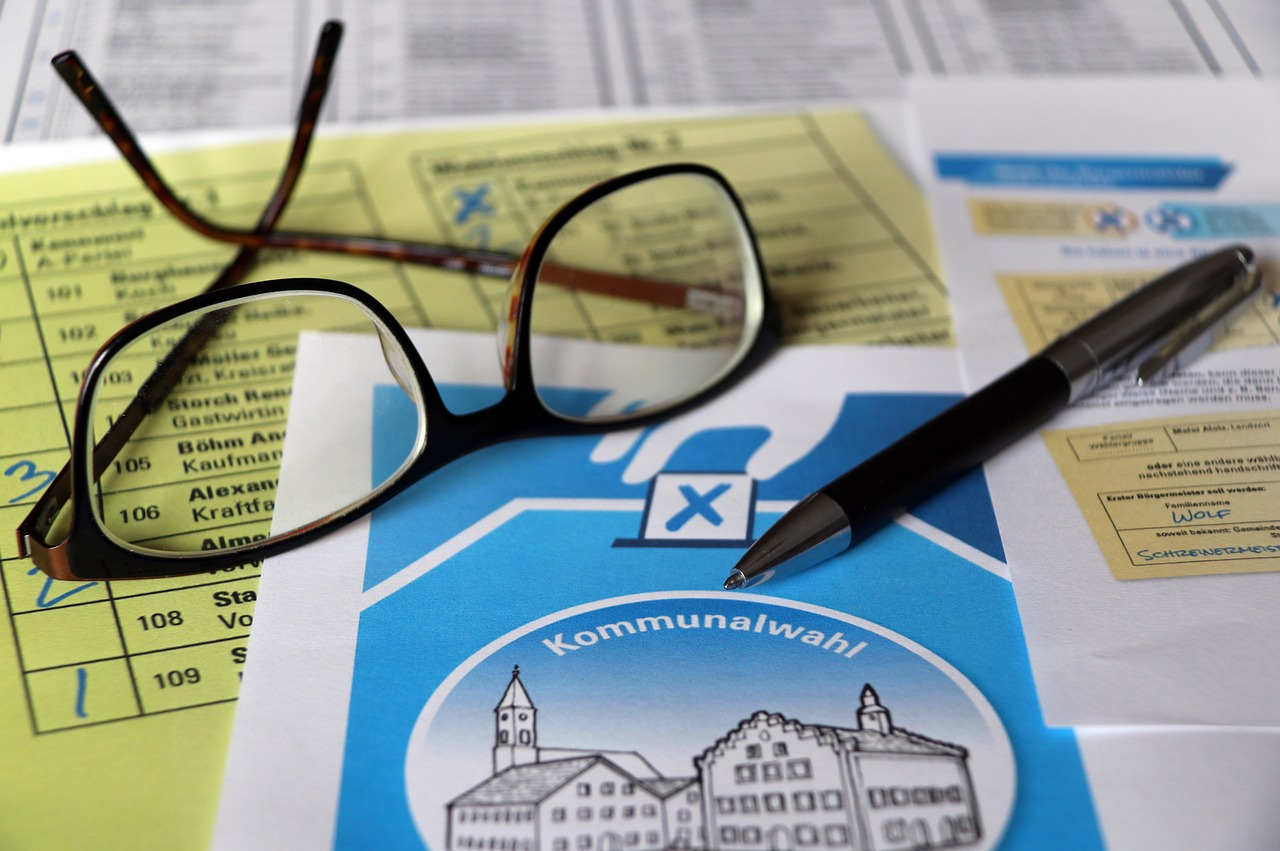 Okulary i długopis na dokumentach wyborczych, sugerujące analizę wyników sondażu politycznego.