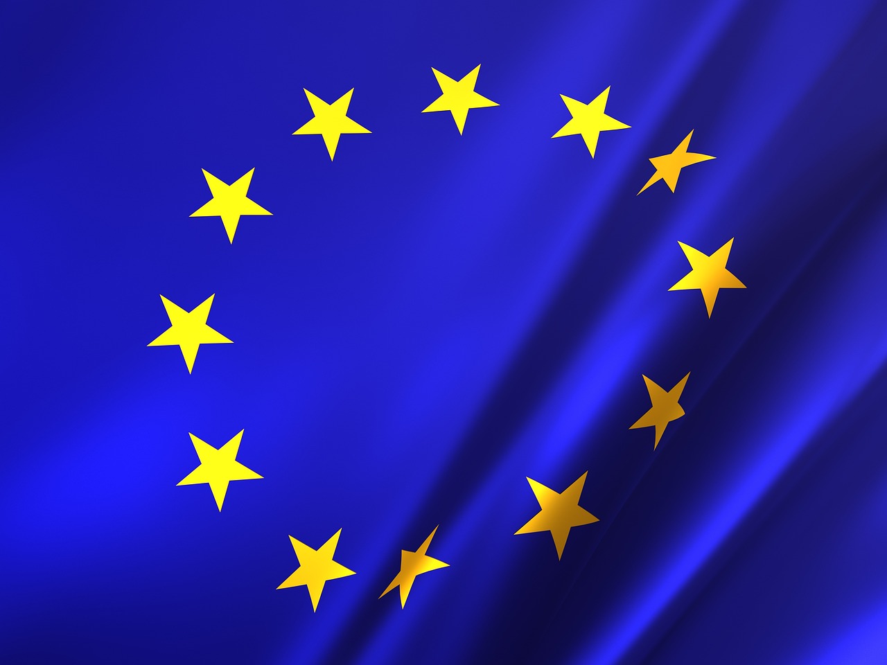 Flaga Unii Europejskiej z kołem żółtych gwiazd na niebieskim tle.