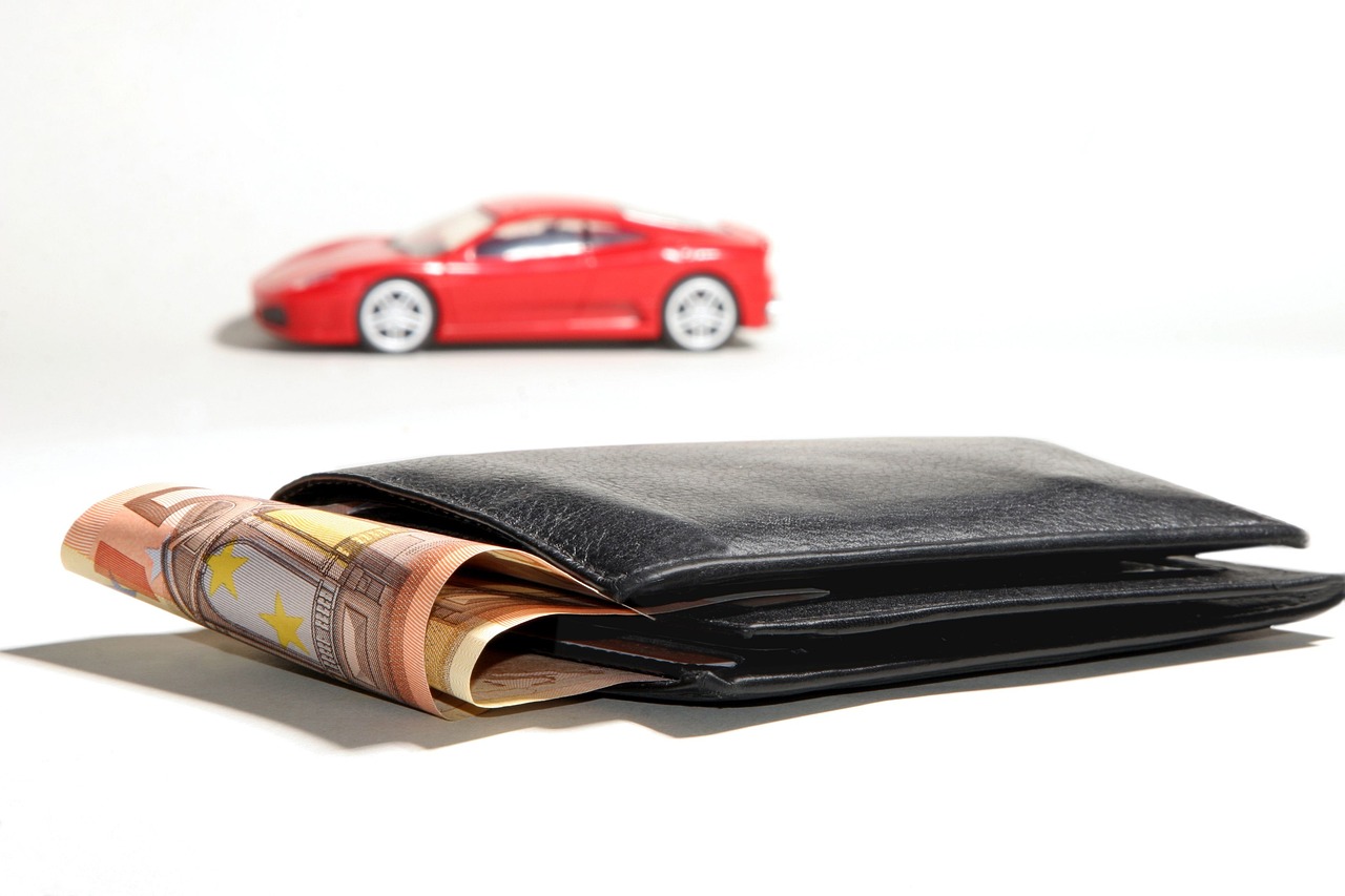 Portfel z euro i czerwony model samochodu symbolizujący problemy finansowe firmy motoryzacyjnej.