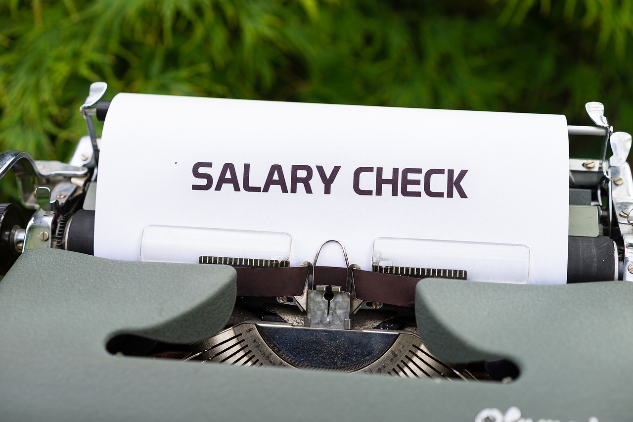 Maszyna do pisania z napisem "SALARY CHECK" na papierze, sugerująca kwestie finansowe i zatrudnienie w JSW.