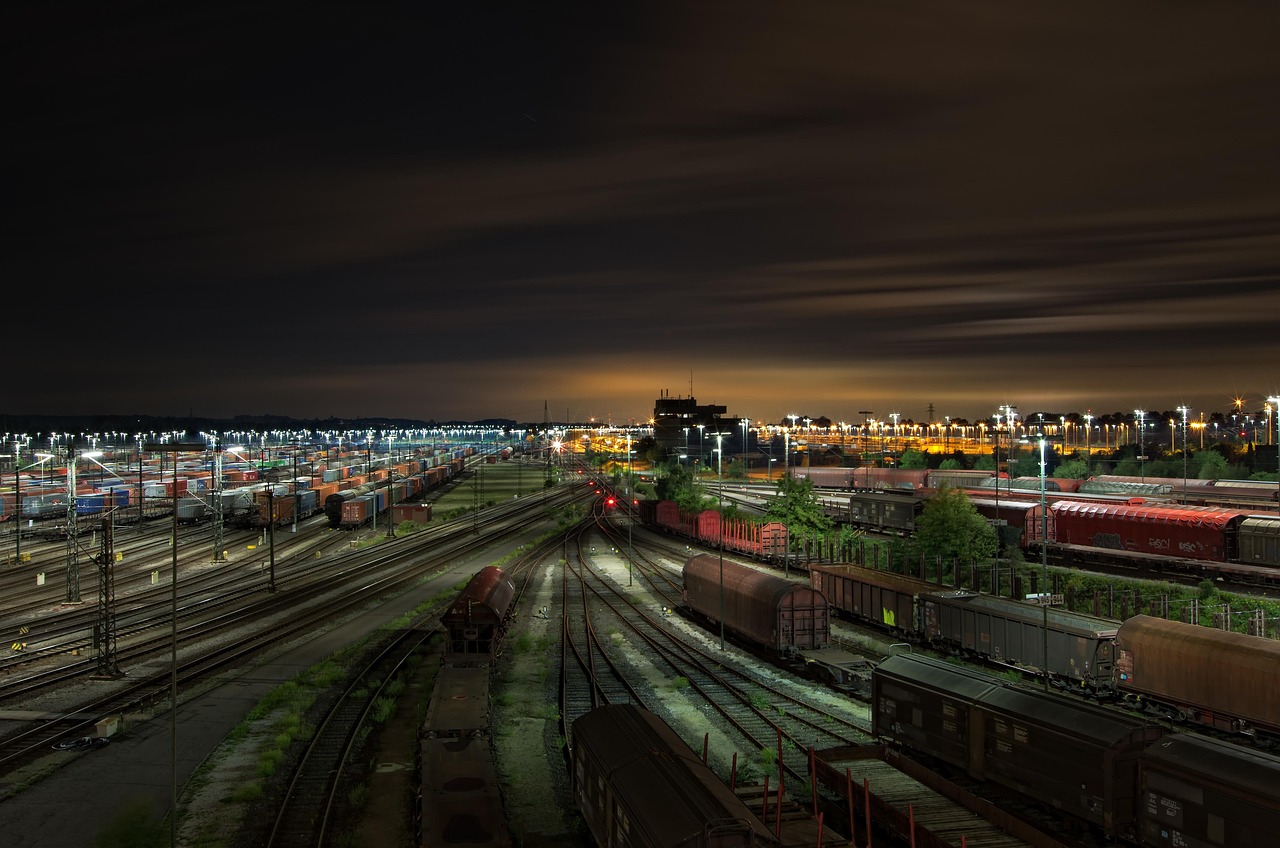 Nocny widok na rozległą stację kolejową z licznymi wagonami towarowymi, ilustrujący logistykę i PKP Cargo.