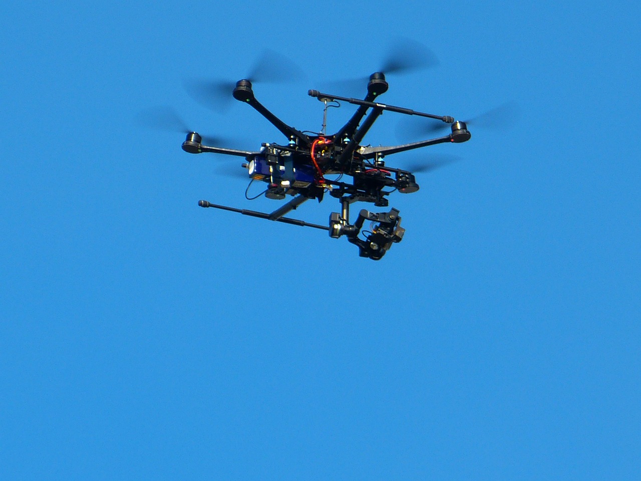 Dron bojowy z kamerą w locie, symbol nowych zagrożeń powietrznych.