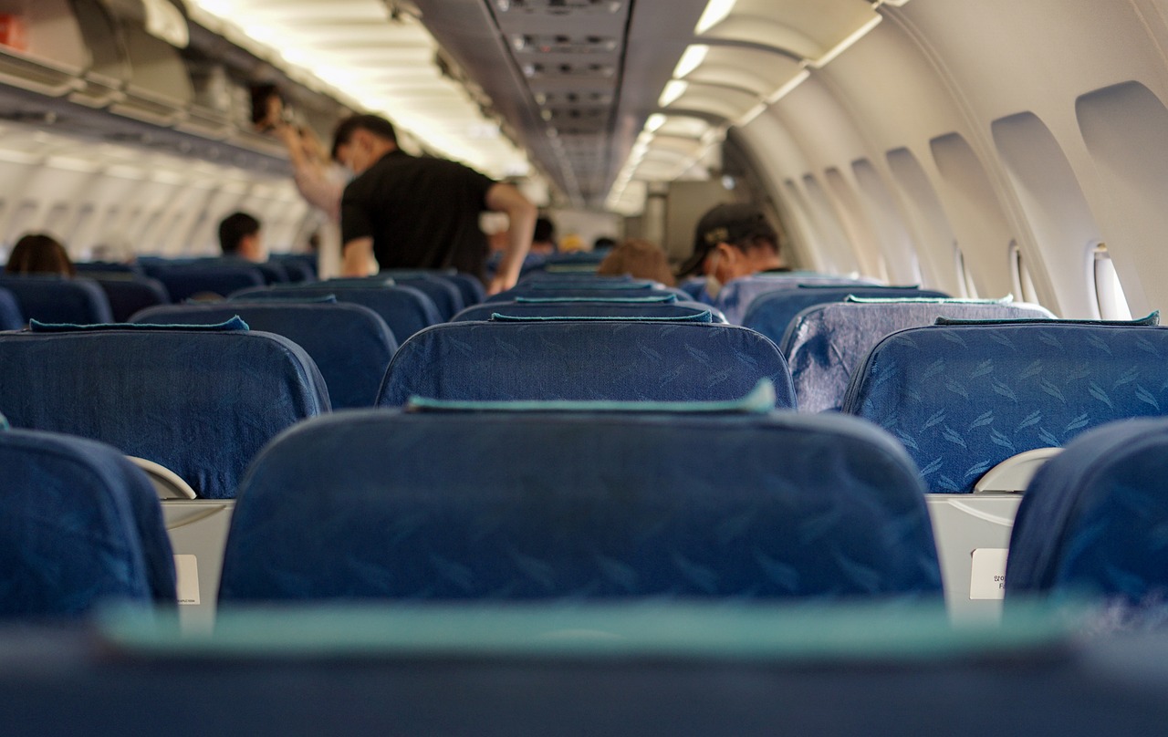 Wnętrze samolotu Dreamliner z niebieskimi siedzeniami i pasażerami