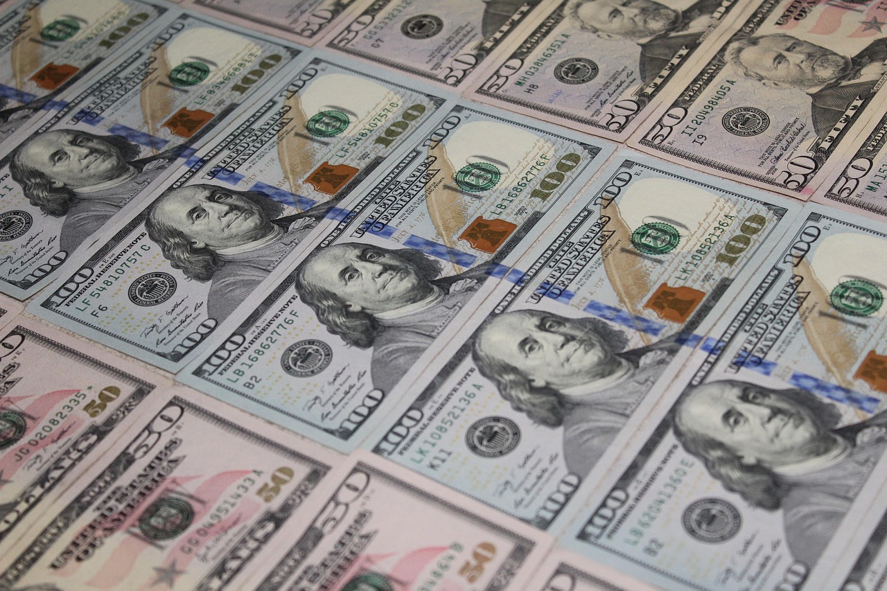Banknoty 100 dolarowe ilustrujące zwiększenie budżetu dla kluczowych urzędów państwowych.