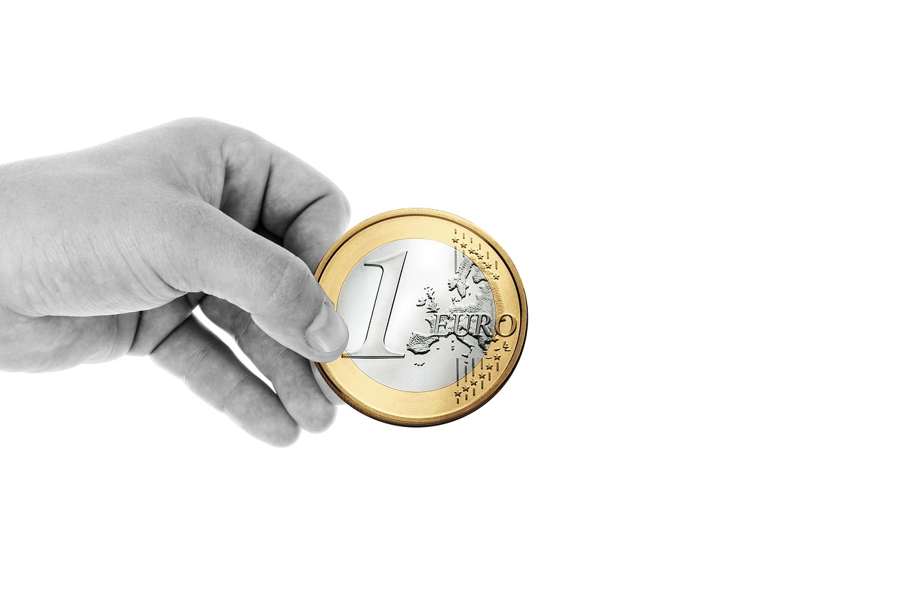 Dłoń trzymająca monetę 1 Euro, symbolizującą analizę finansową incydentu lotniczego.