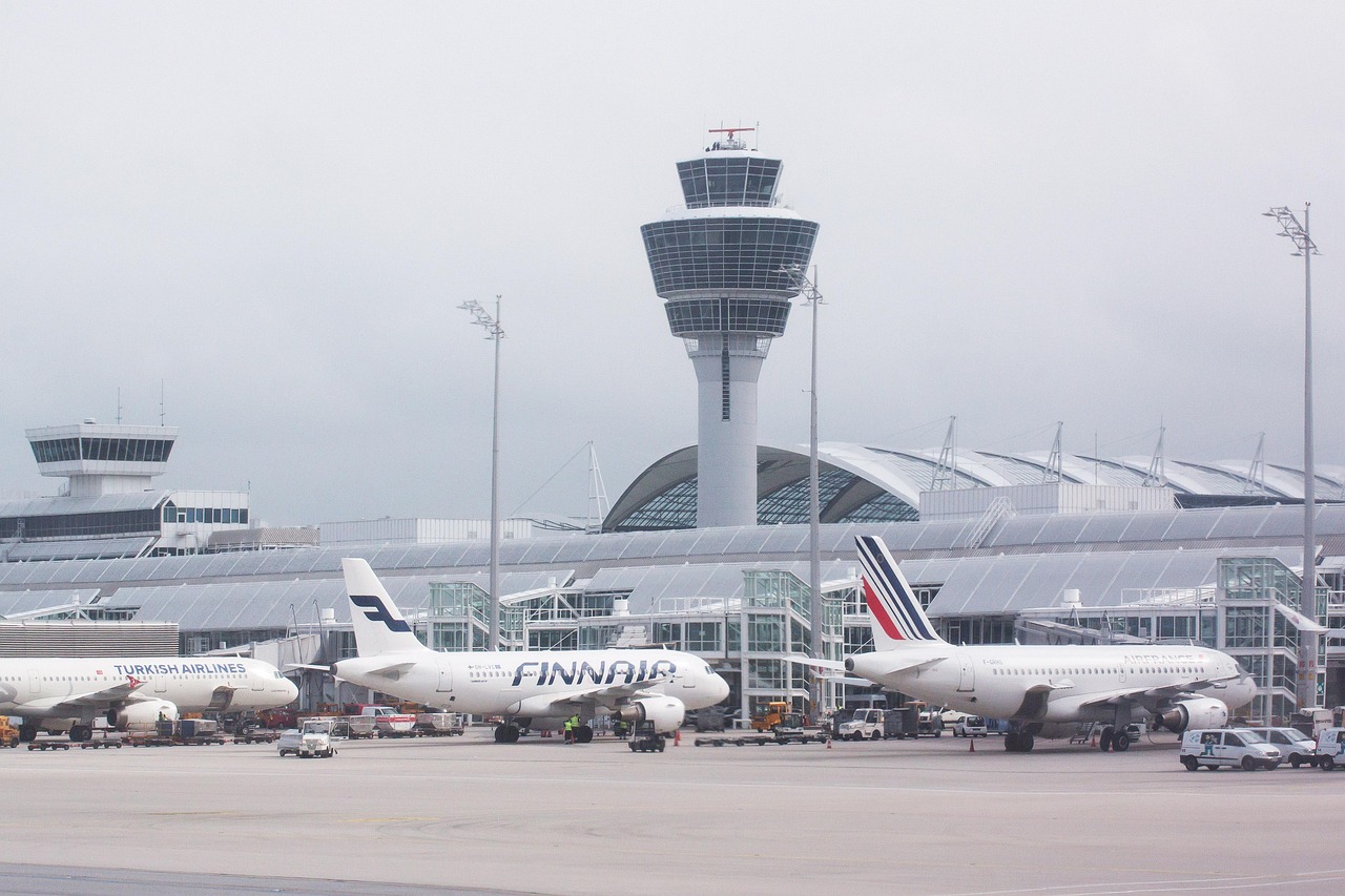Lotnisko z wieżą kontroli lotów i zaparkowanymi samolotami, w tym Boeingiem.