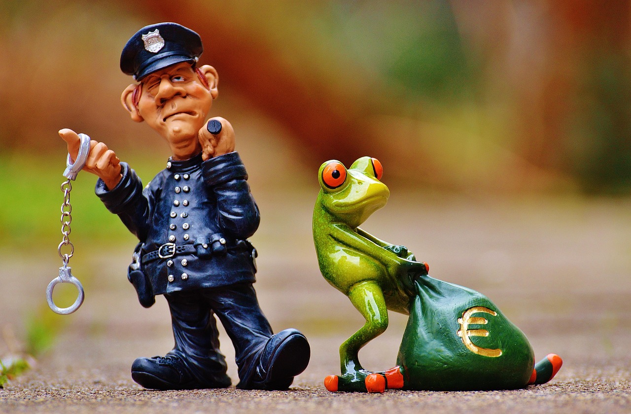 Figurka policjanta z kajdankami obok żaby niosącej worek z symbolem euro, nawiązanie do kradzieży roweru za 70 tys. zł.