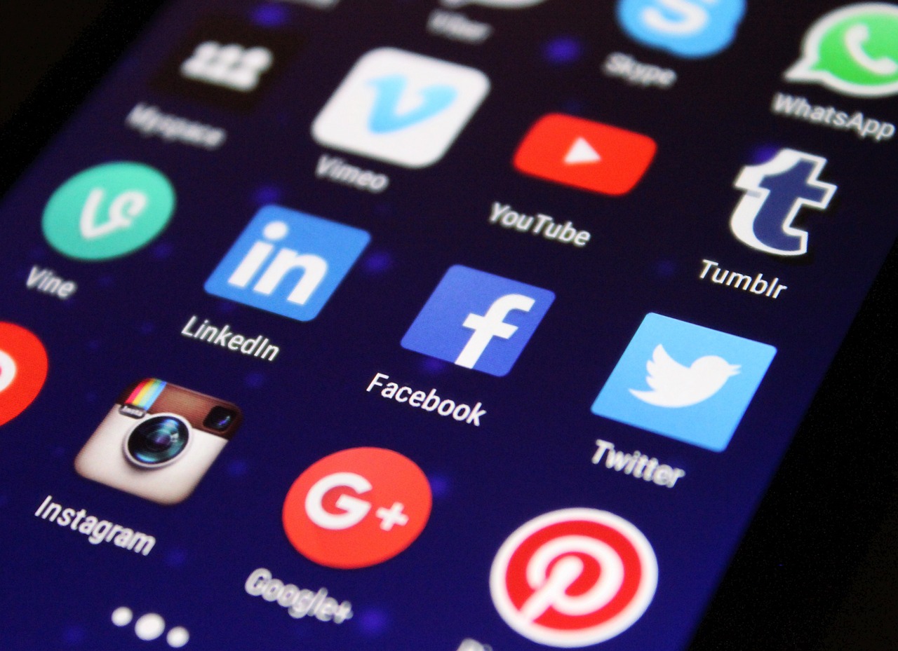 Ikony mediów społecznościowych na ekranie smartfona, w tym Twitter, Facebook, Instagram i YouTube, symbolizujące presję polityczną na wolność mediów.