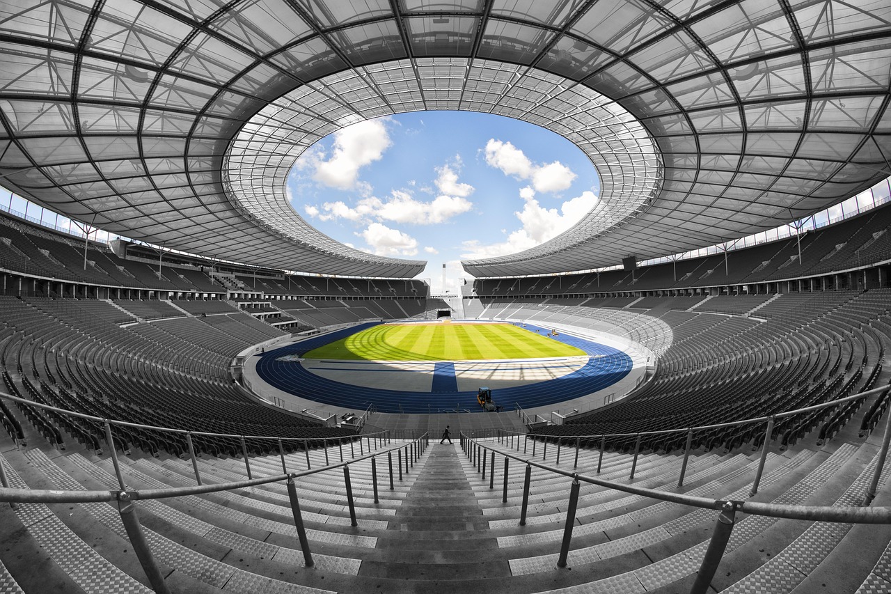 Stadion olimpijski z bieżnią i murawą, symbol sportowej rywalizacji.