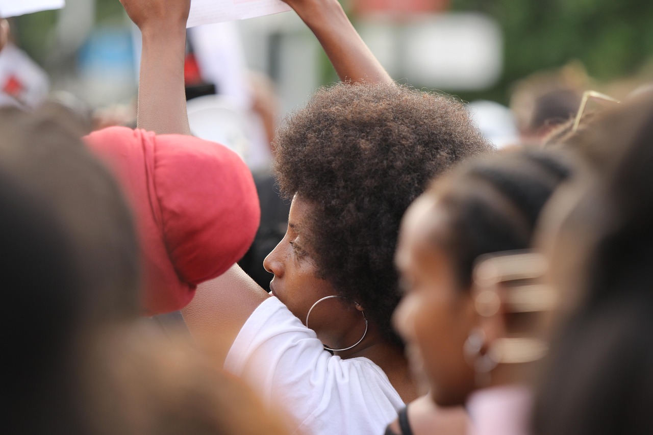 Kobieta z afro włosami na proteście, symbolizująca ruch antifa.