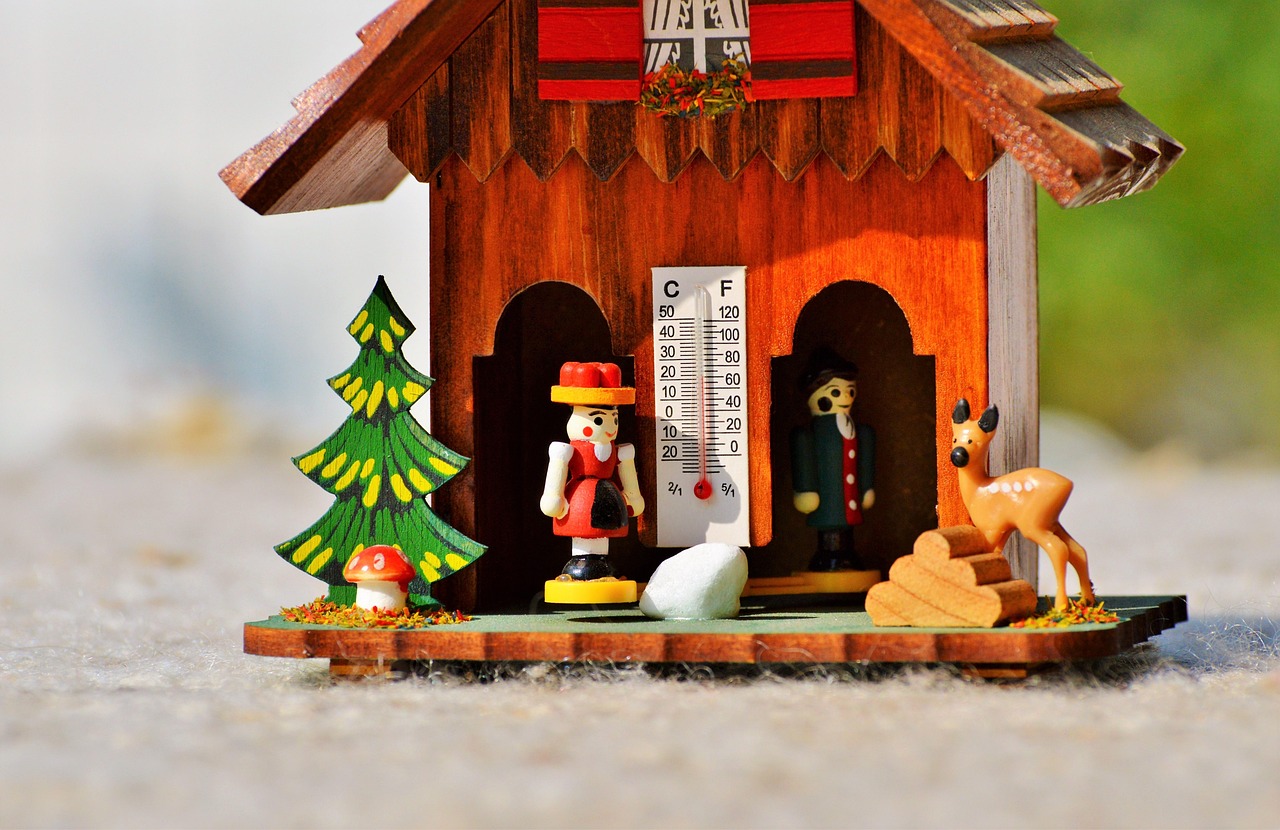 Drewniany domek z termometrem pokazującym spadek temperatury, symbolizujący koniec lata.