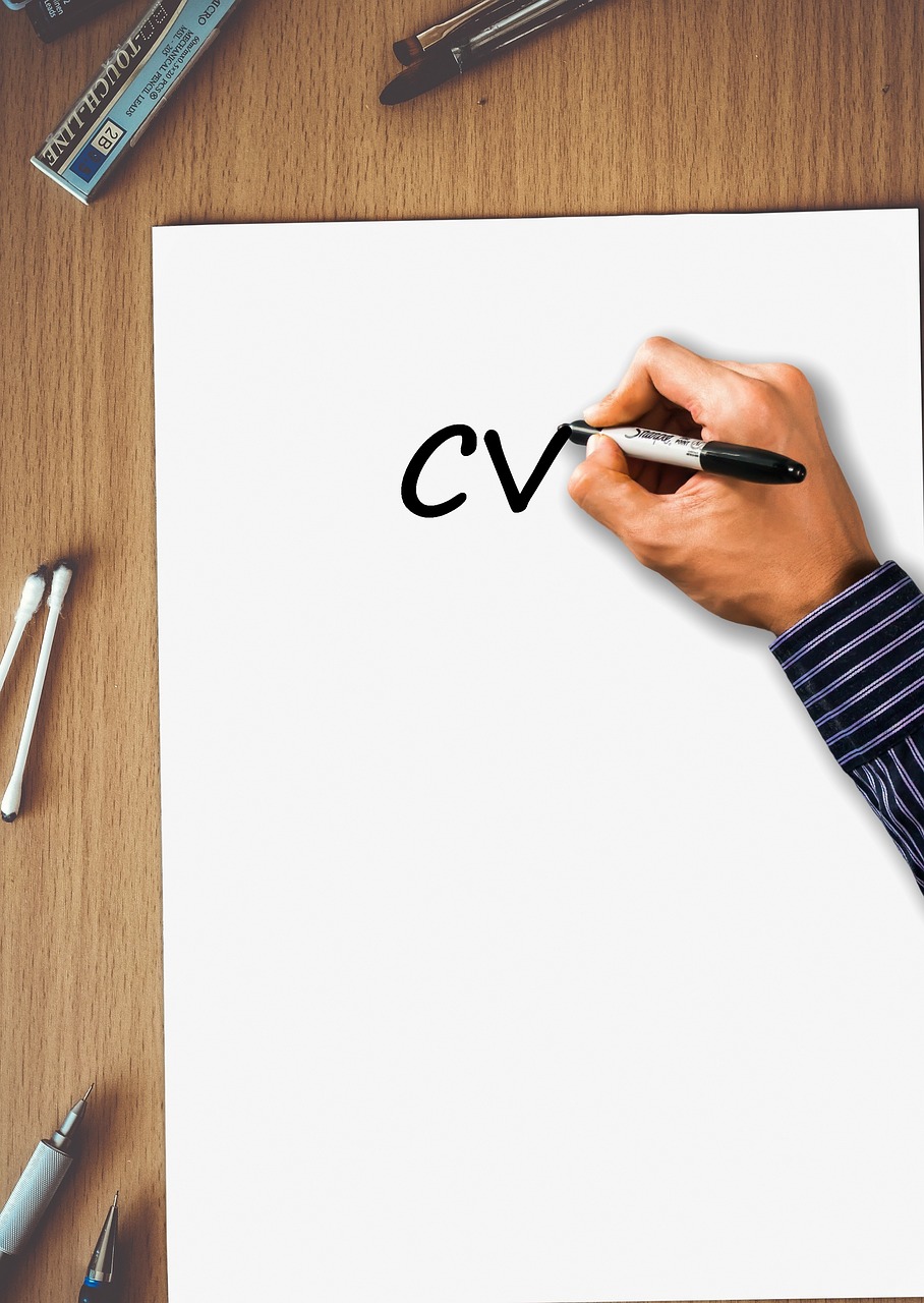 Ręka pisze CV na białej kartce, symbolizując obcięte etaty katechetów.