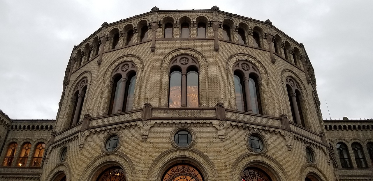 Budynek Stortinget w Oslo, norweski parlament, w tle pochmurne niebo.