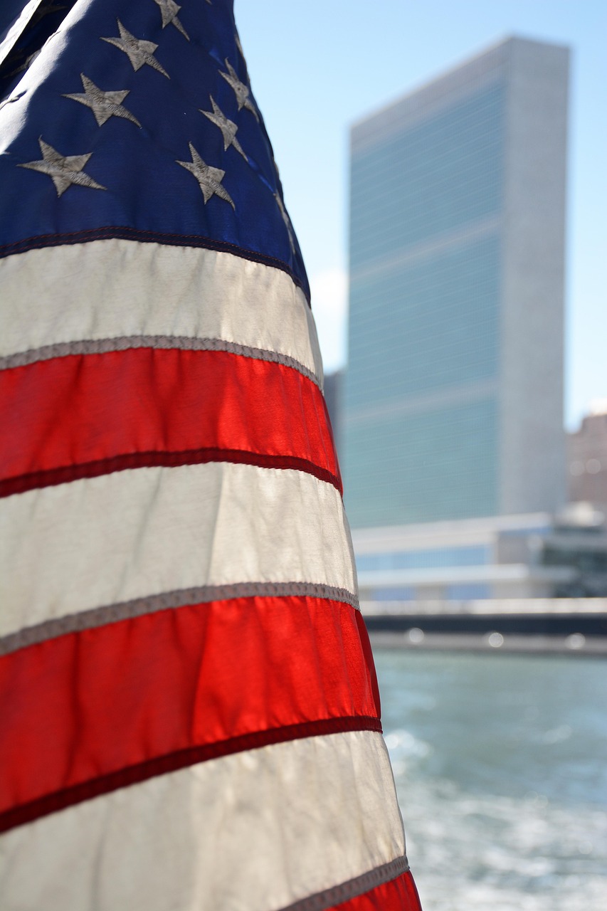 Flaga USA na tle budynku ONZ, symbolizująca dyplomatyczne otwarcie Polski wobec Syrii.