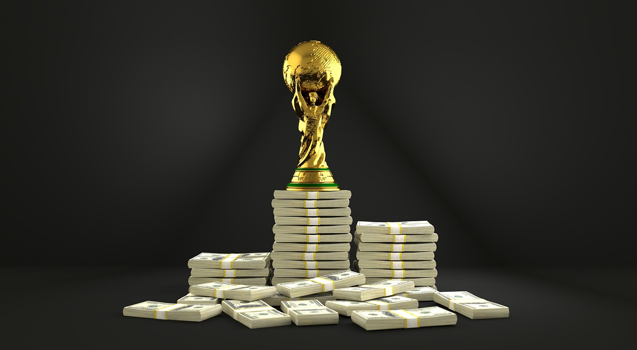 Puchar Świata FIFA na stosach pieniędzy symbolizujący nagrody i pieniądze w piłce nożnej.