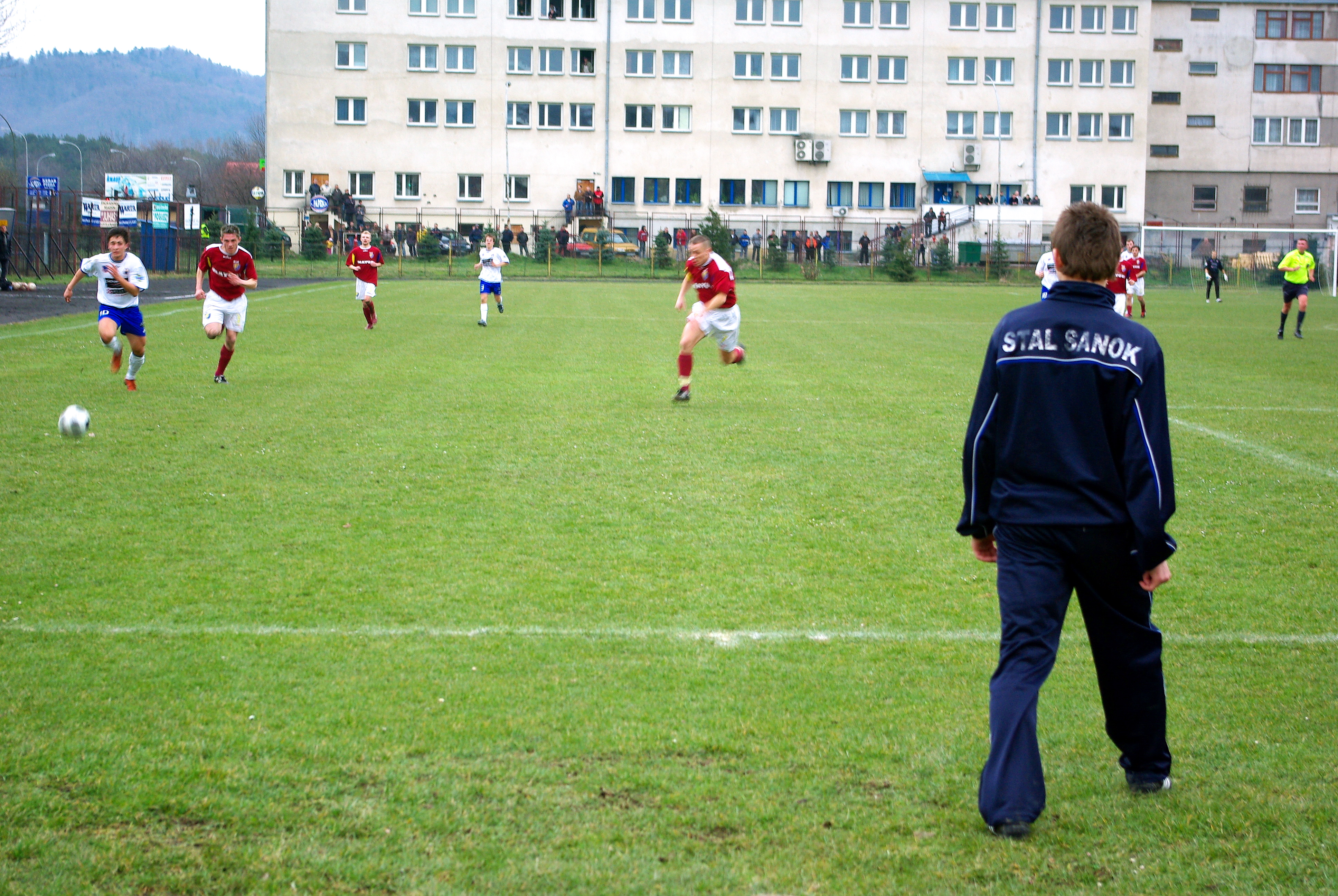Piłkarze Stali Mielec na boisku, jeden z nich ma na kurtce napis "STAL SANOK".