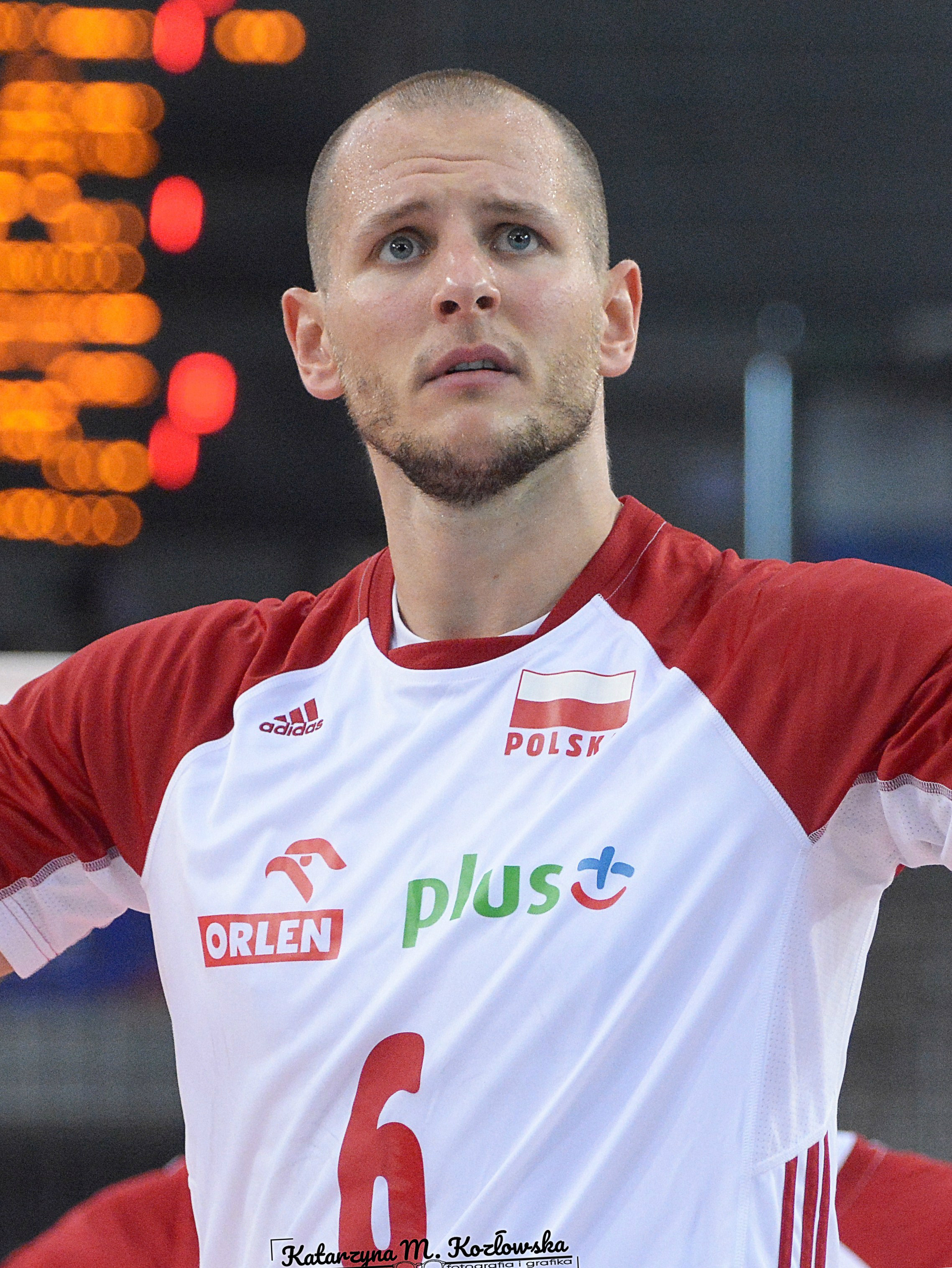 Bartosz Kurek, kapitan polskiej reprezentacji siatkówki, w białej koszulce z orłem i napisem "POLSK".