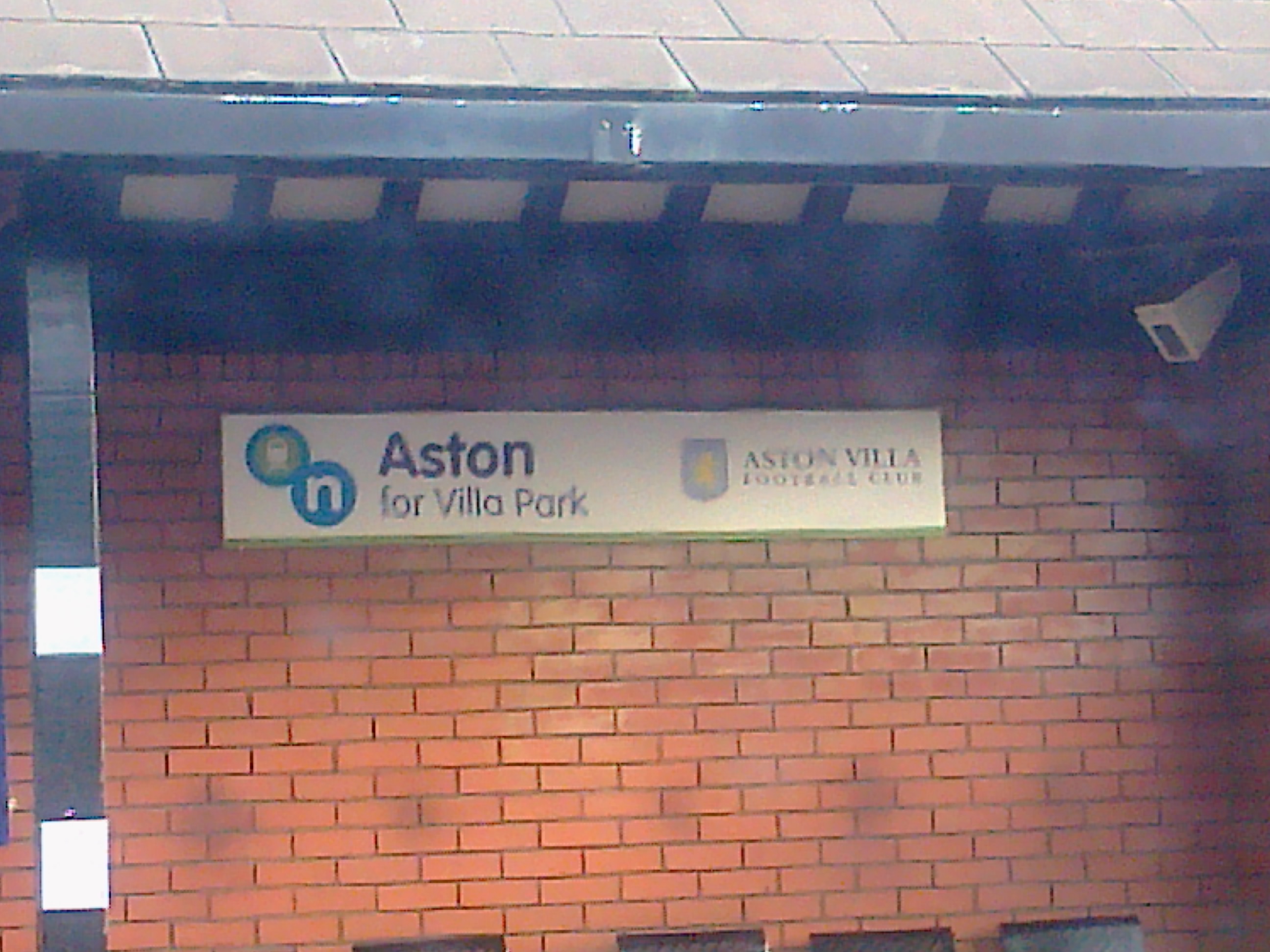 Znak "Aston for Villa Park" i logo Aston Villa Football Club na ceglanej ścianie.
