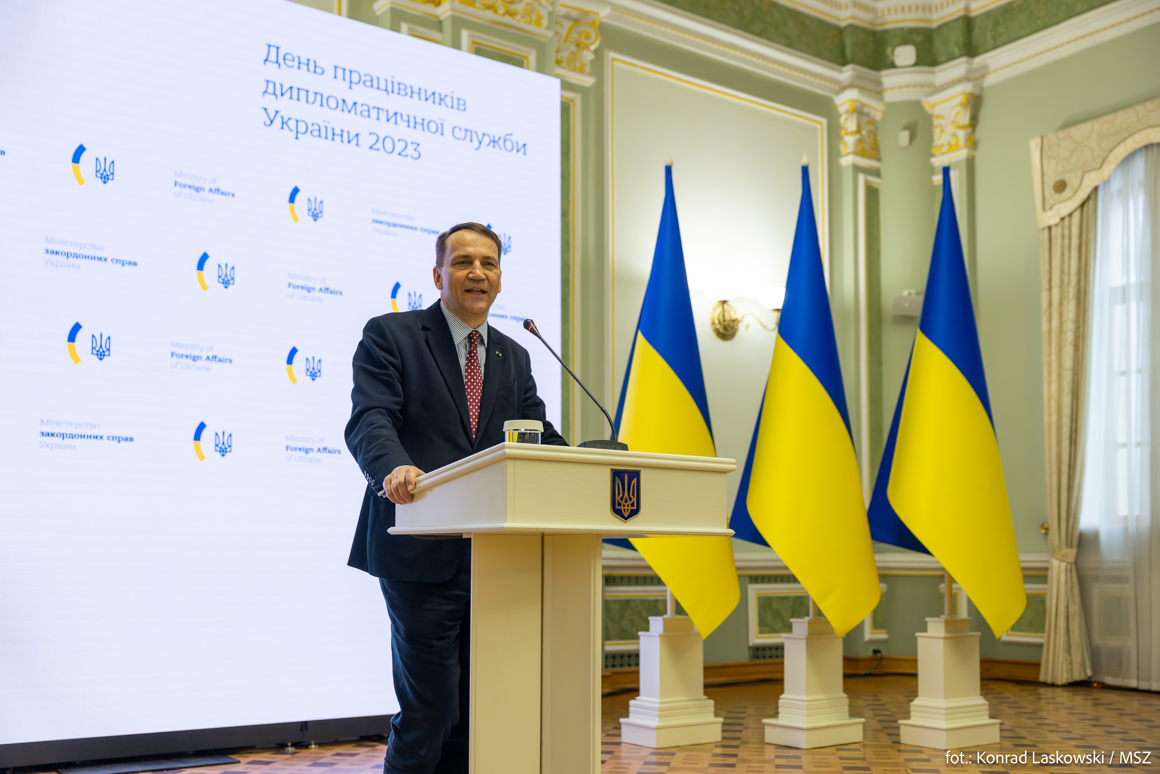 Radosław Sikorski przemawia na tle flag Ukrainy, omawiając warunki pokoju w Ukrainie.