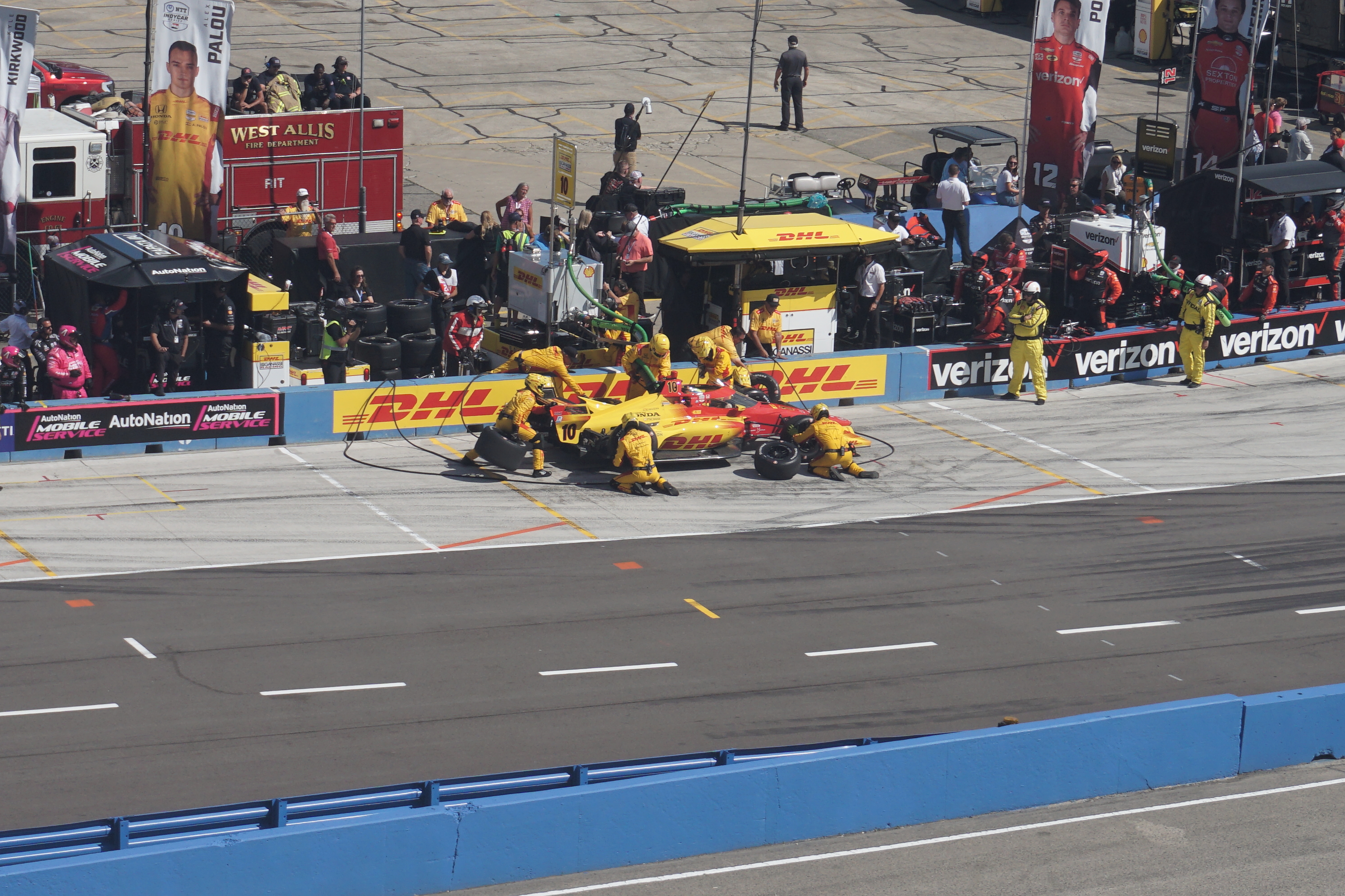 Alex Palou w żółtym kombinezonie podczas pit stopu w wyścigu IndyCar, z numerem 10 na samochodzie.