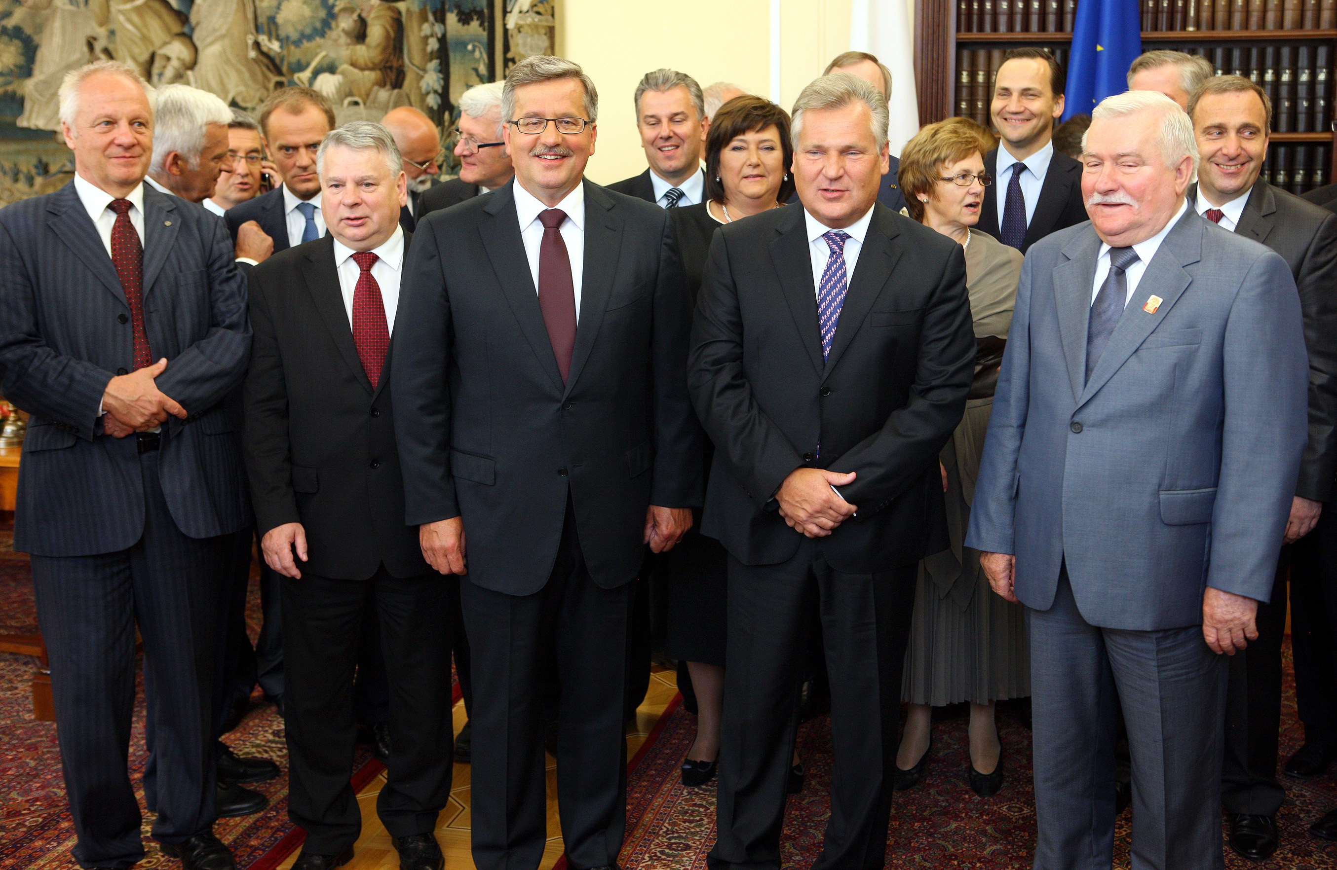 Lech Wałęsa w szarym garniturze podczas kontroli SOP, obok inni politycy.