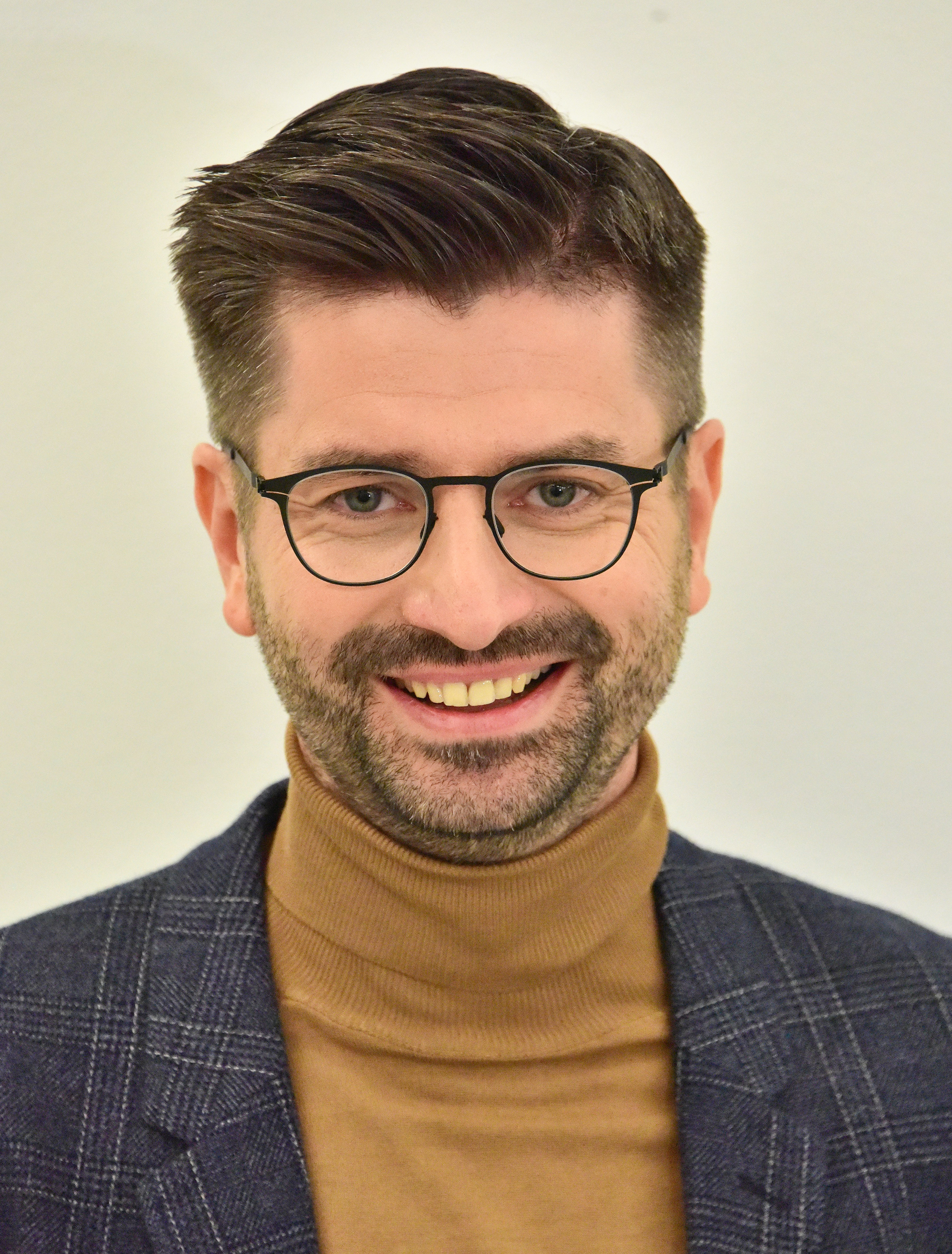 Krzysztof, Człowiek Roku 2025, w eleganckim stroju, z okularami.